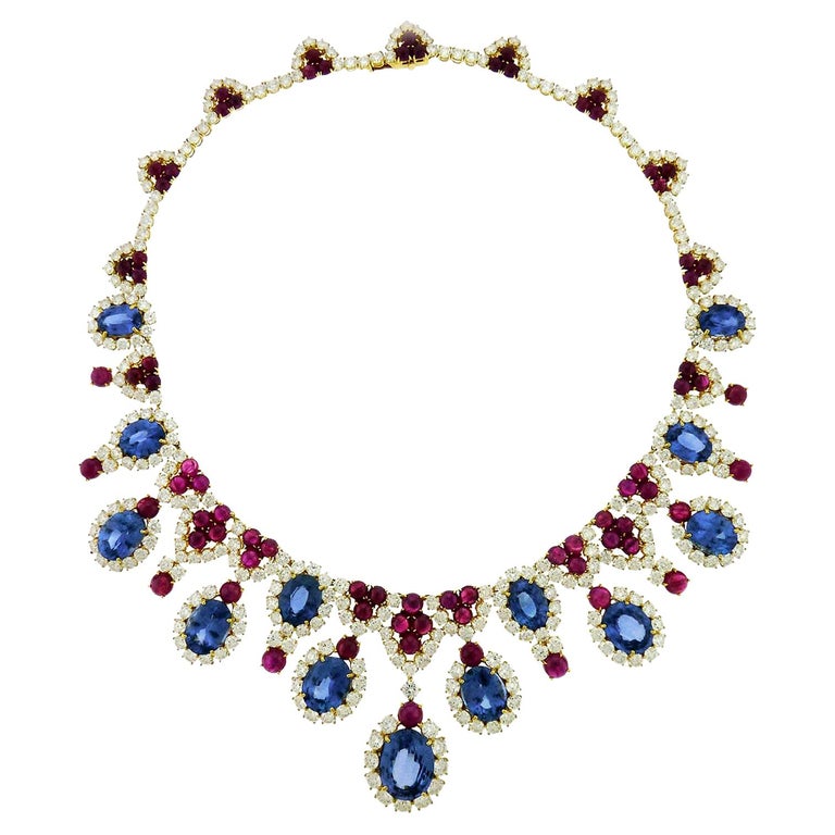 An elegant and sophisticated sapphire, ruby and diamond necklace by Bulgari. 
Set at the front with 13 oval-cut sapphire and diamond clusters scatter among 
cabochon rubies and diamond trefoils, suspending oval-cut sapphire and round-cut diamond