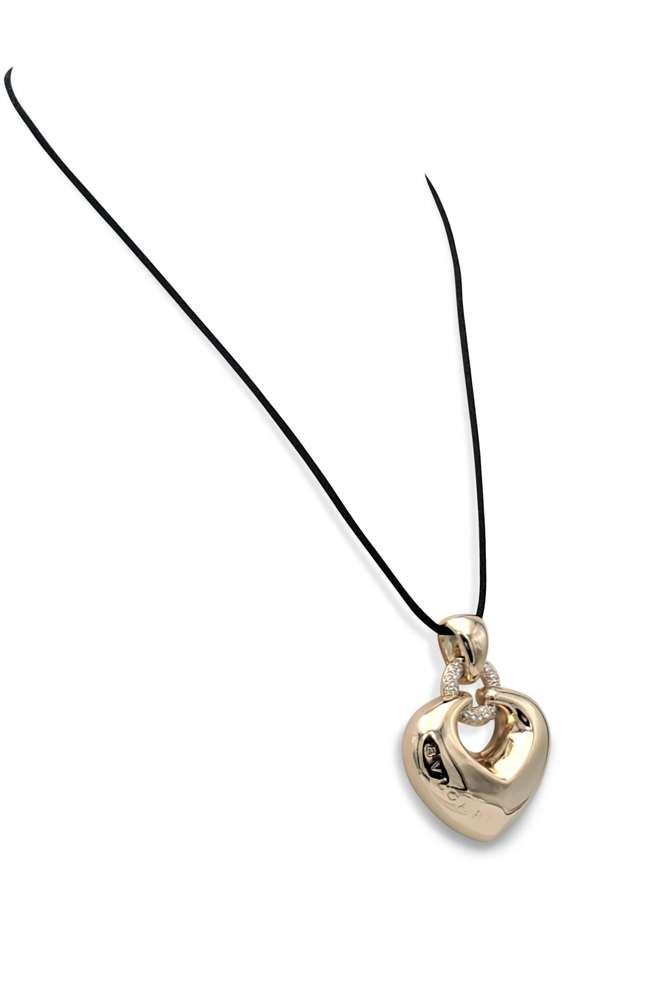 Authentic Bulgari puffed heart pendant from the 'Doppio Cuore' collection is crafted in 18 karat yellow gold and set with an estimated 0.60 carats of high-quality round brilliant cut diamonds. The pendant hangs from a silk cord that is not original