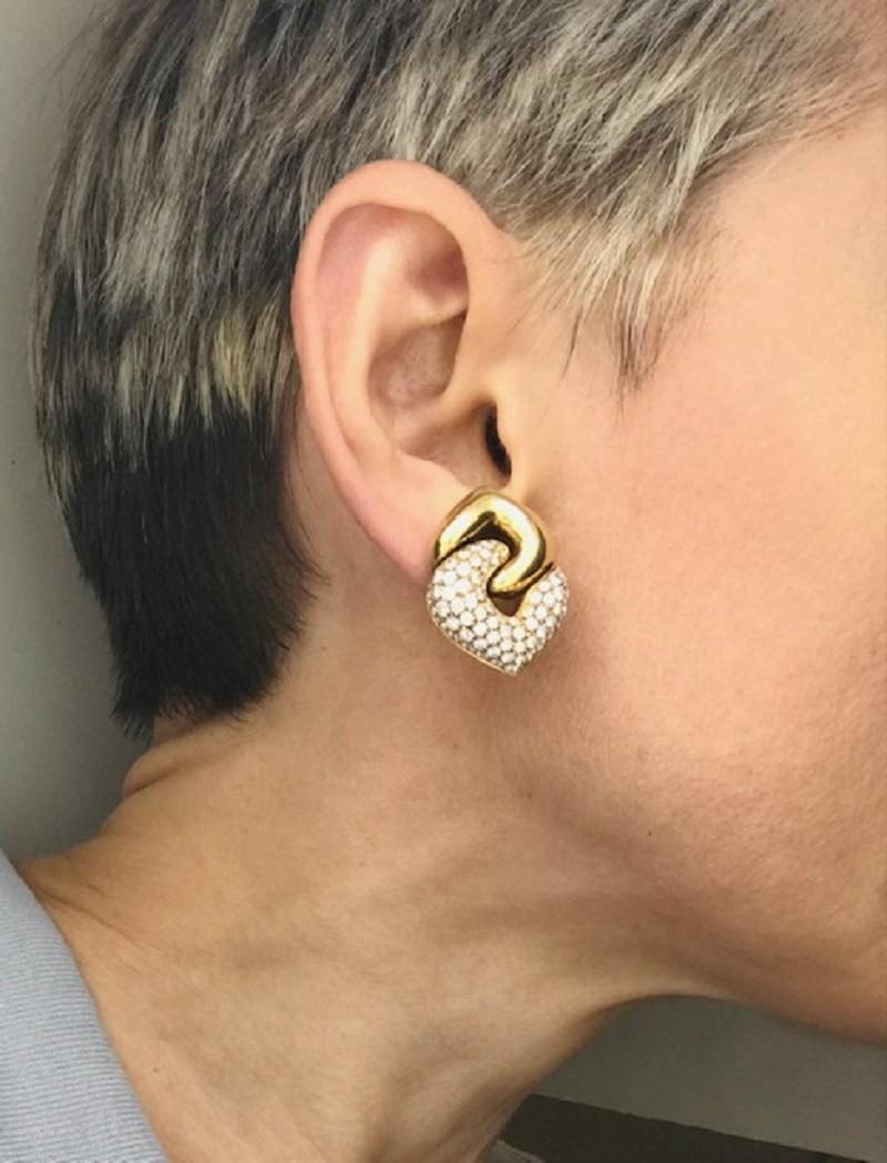 Ein Paar der klassischen Bulgari Doppio Cuore Ohrringe aus Gelbgold mit Diamanten.
Die Ohrringe sind in Form von zwei ineinandergreifenden Herzen gestaltet: Ein goldenes Herz mit umgekehrtem Kopf hält ein diamantenes. Dieses Paar ist das größte in