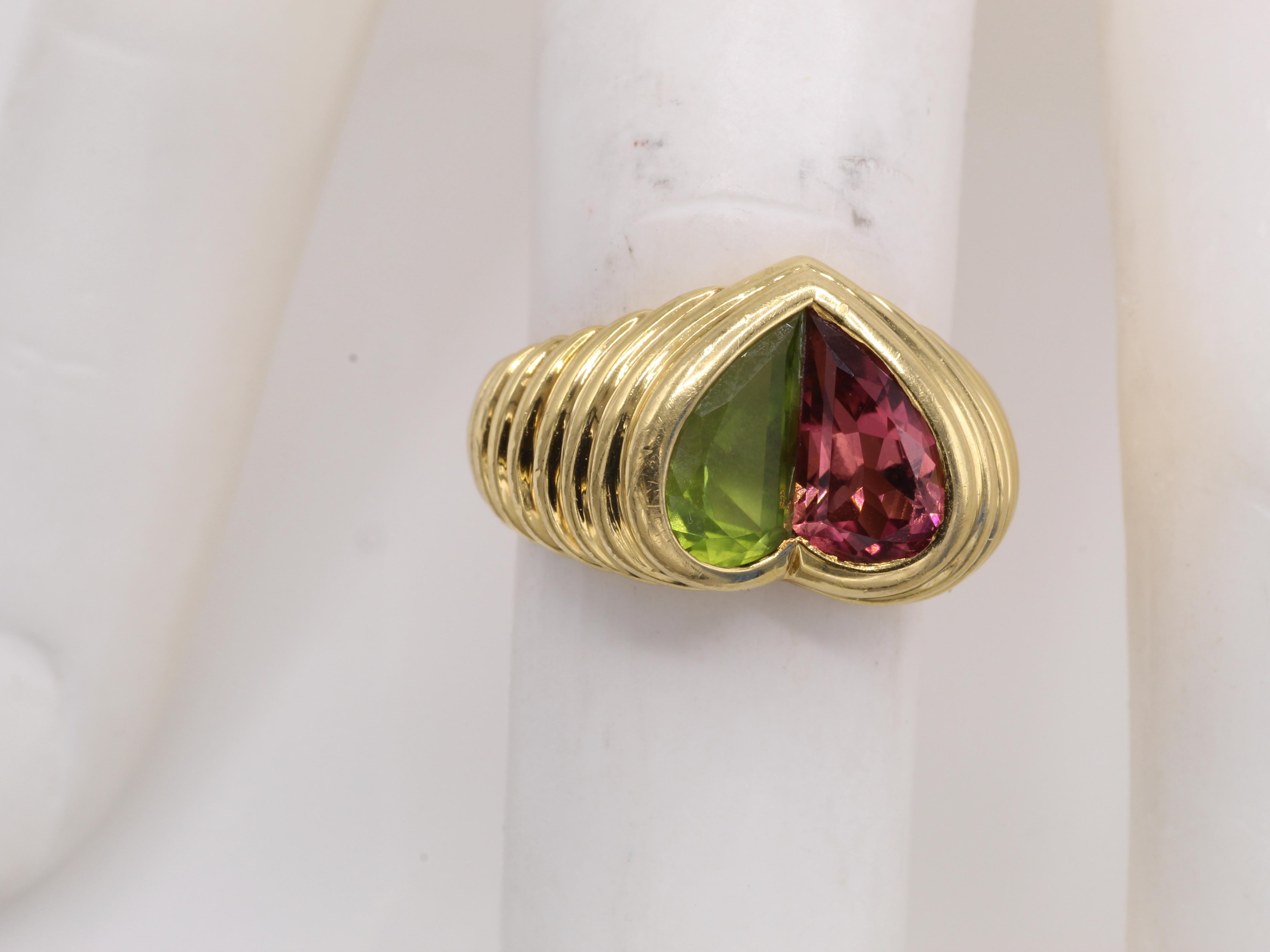 Beautifully designed and masterfully handcrafted by the renown Italian jeweler Bulgari this ring features 2 halves of one heart set with a vibrant pink tourmaline and peridot. 18 karat yellow gold and signed on the inside of the shank BVLGARI, 750