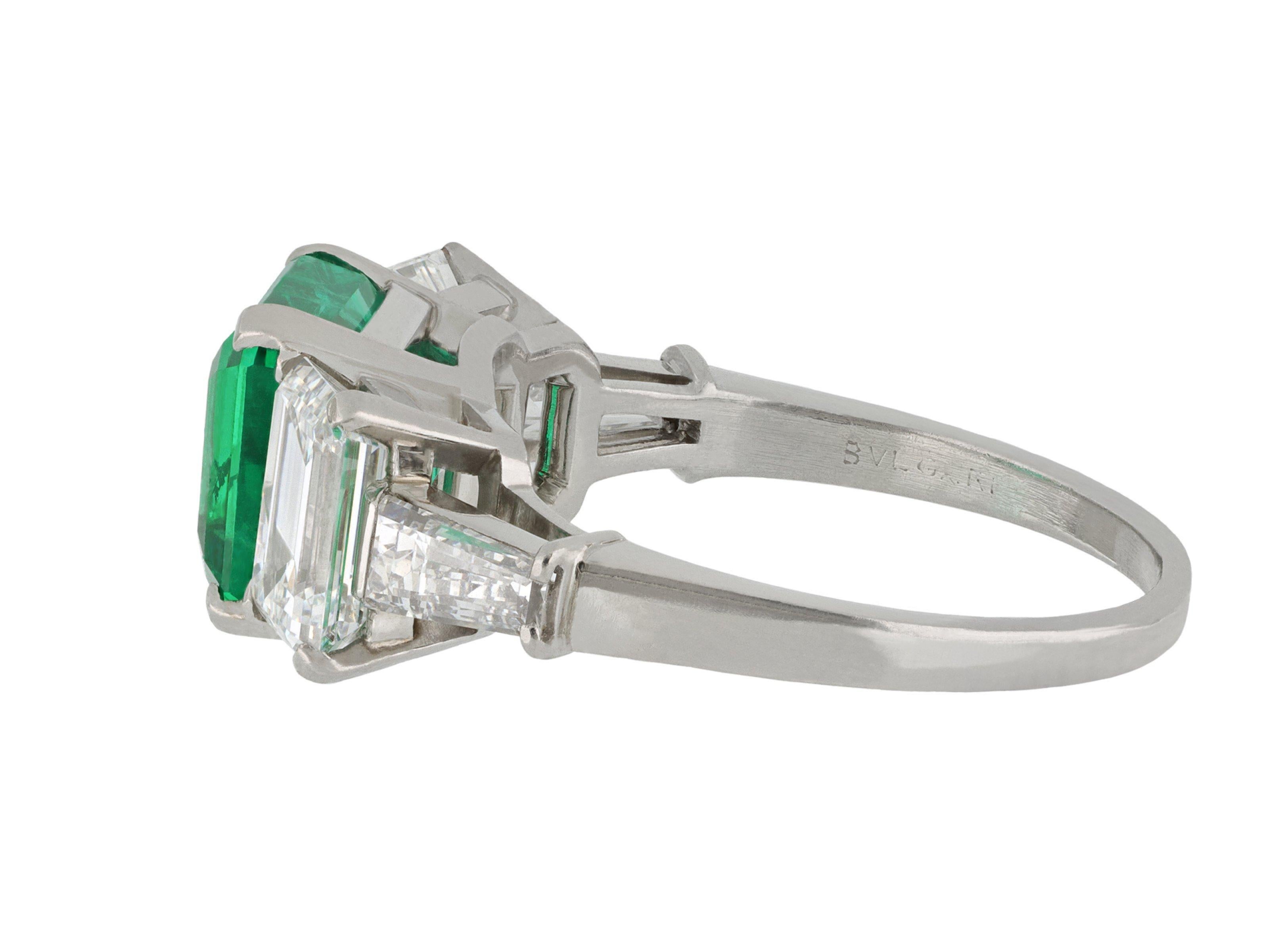 Bulgari emerald and diamond ring. Set to centre with a square emerald cut natural Colombian emerald with minor clarity enhancement in a open back claw setting with an approximate weight of 2.09 carats, flanked by two octagonal emerald cut diamonds
