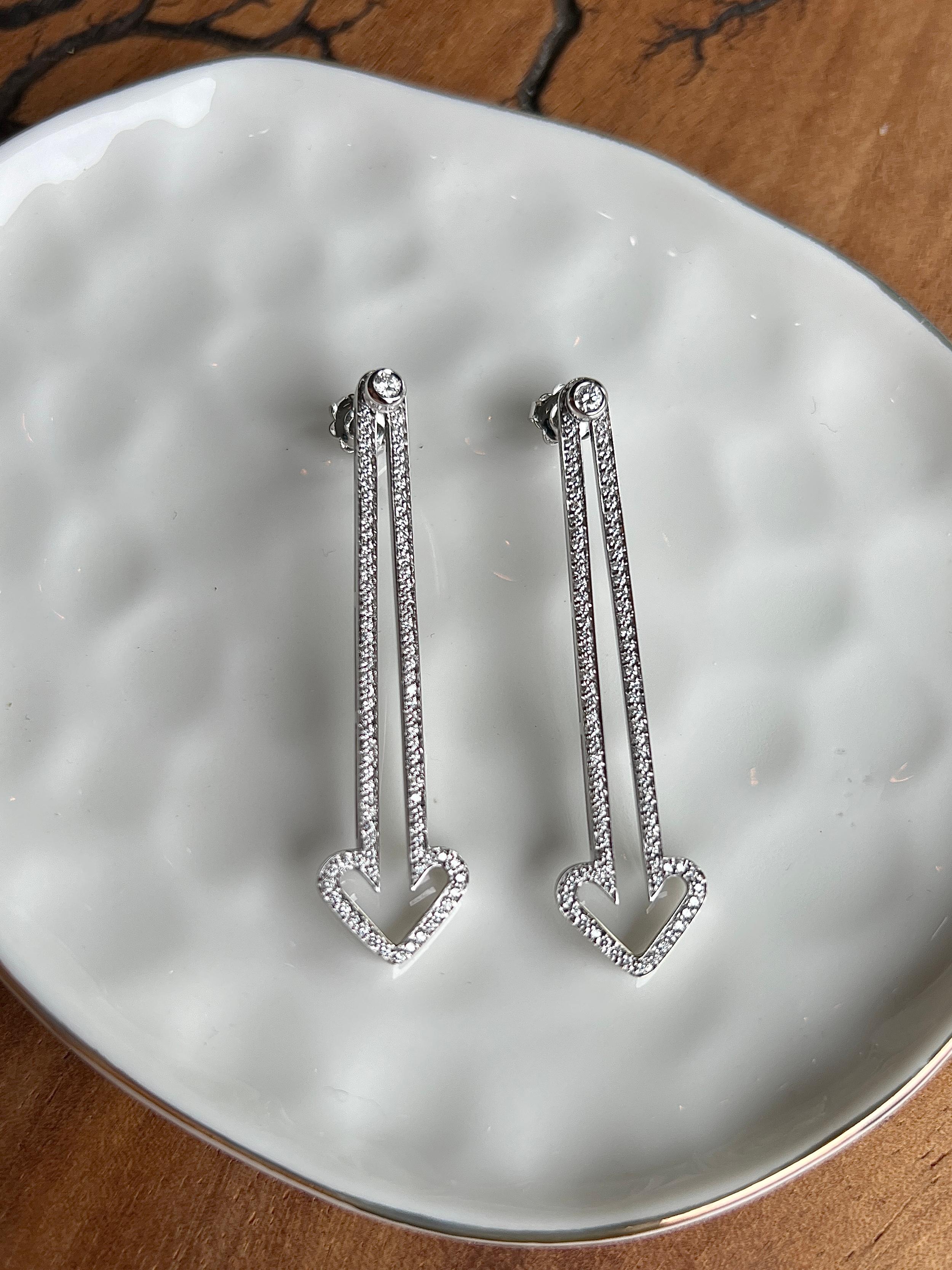 Un paio di orecchini in oro bianco 18 carati di Enigma by Gianni Bulgari, un marchio di lusso fondato nel 1989 che unisce un design audace a una raffinata lavorazione artigianale italiana. Questi straordinari orecchini lineari a goccia sono