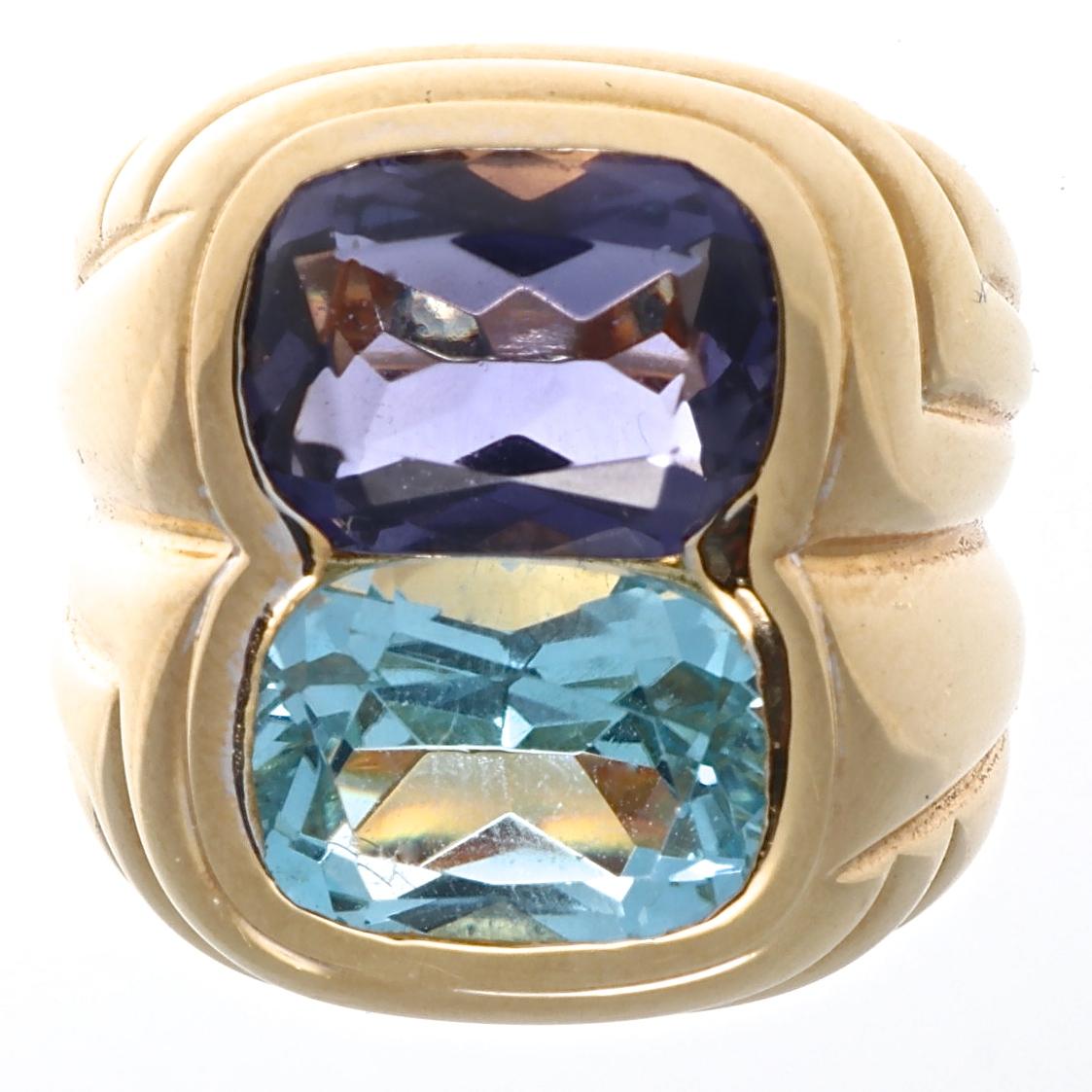 Quintessentially bold and colorful. Two characteristics integral to Bulgari's designs. Featuring vibrant blue topaz and glowing purple iolite rolled into contours of 18k yellow gold. Signed Bvlgari. Ring size 5 and can easily be resized to fit, if