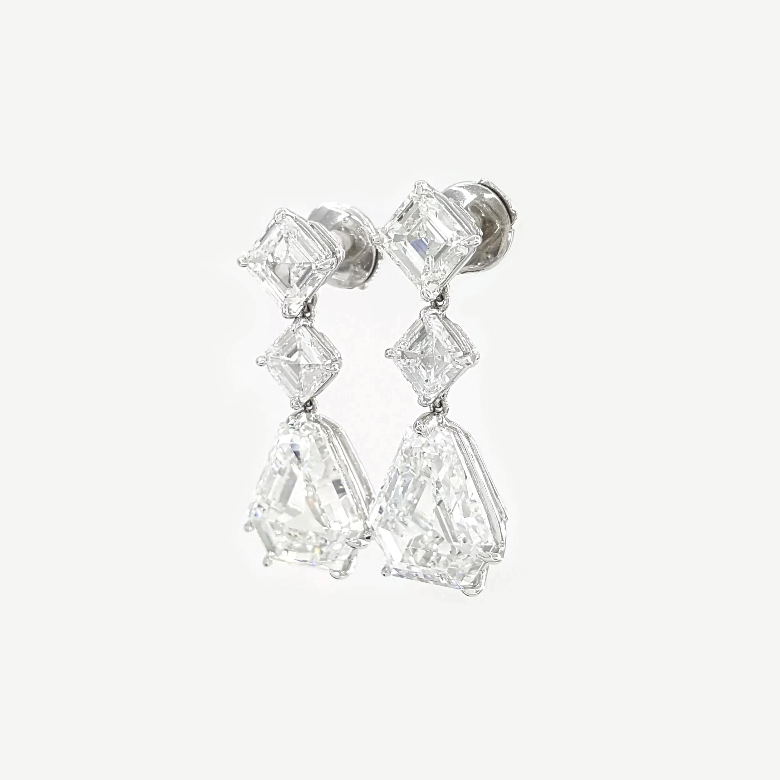 A pair of exquisite Bvlgari drop earrings featuring a total diamond weight of 13.97 carats. These earrings weigh 8.4 grams and are adorned with six natural shield and square emerald-cut diamonds, showcasing colors ranging from D to F and clarity