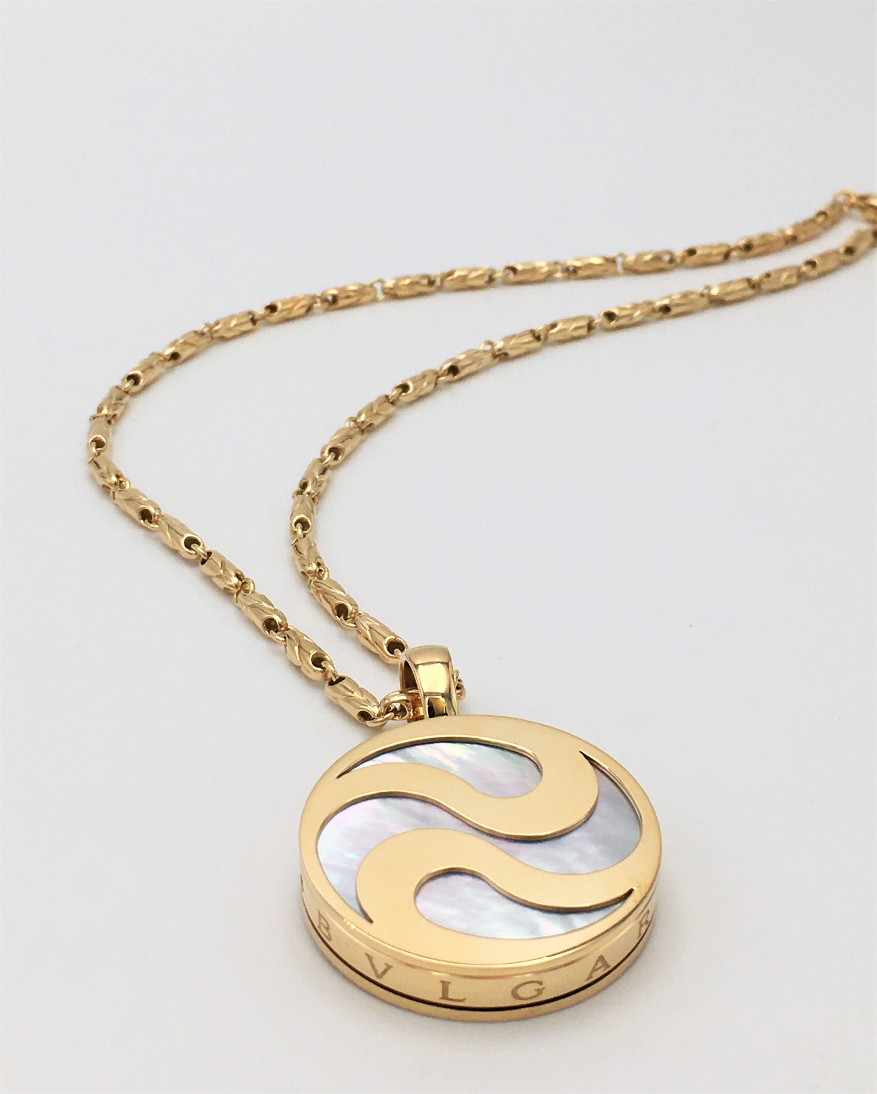 Authentic Bulgari pendant features a spinning mother-of-pearl stone inlaid in a swirling Yin Yang design yellow gold disc. The pendant hangs from an 18 karat yellow gold link chain measuring 15 1/2 inches in length. Signed Bulgari, 750, Made in