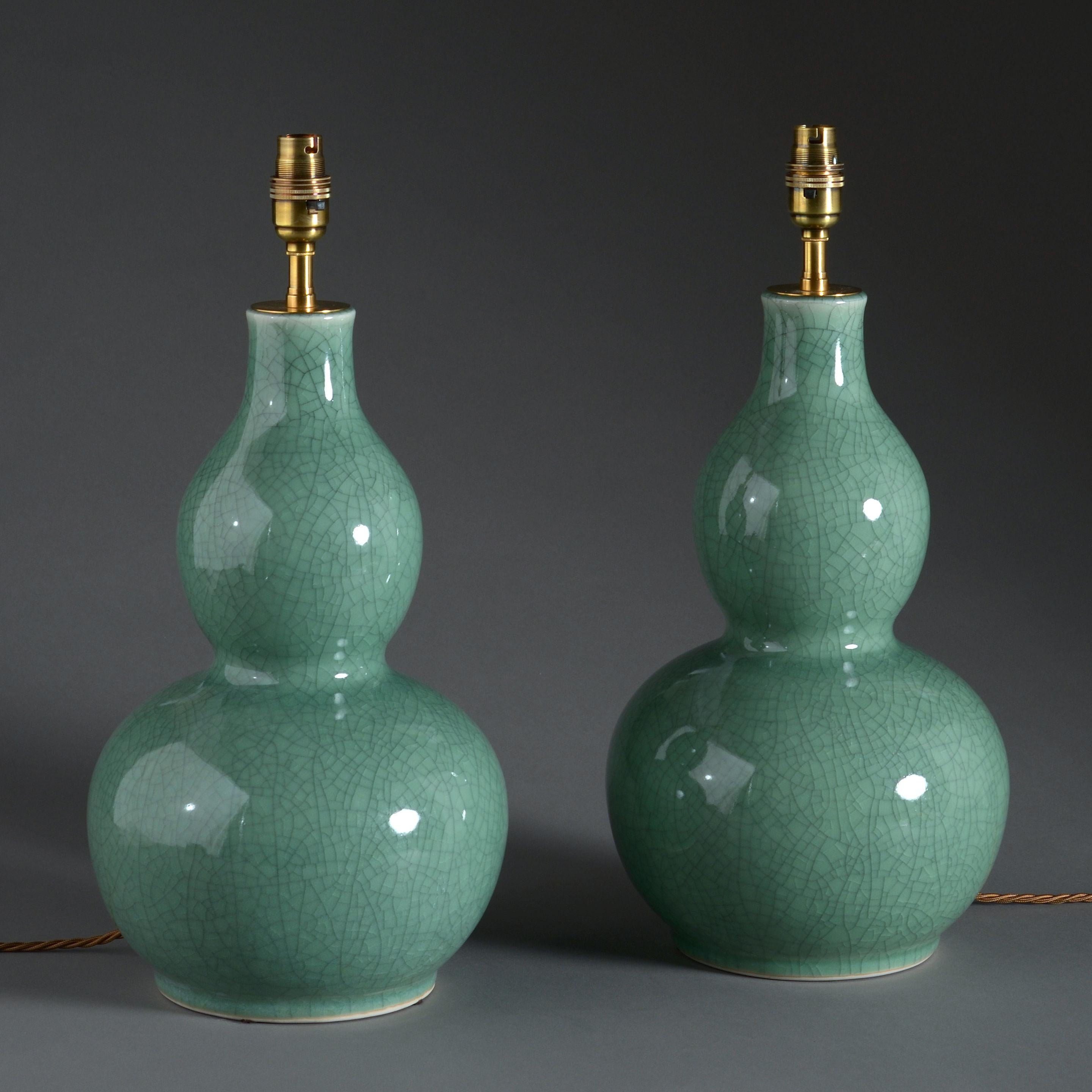 A pair of crackle glazed celadon porcelain gourd vases, mounted as lamp bases.
      