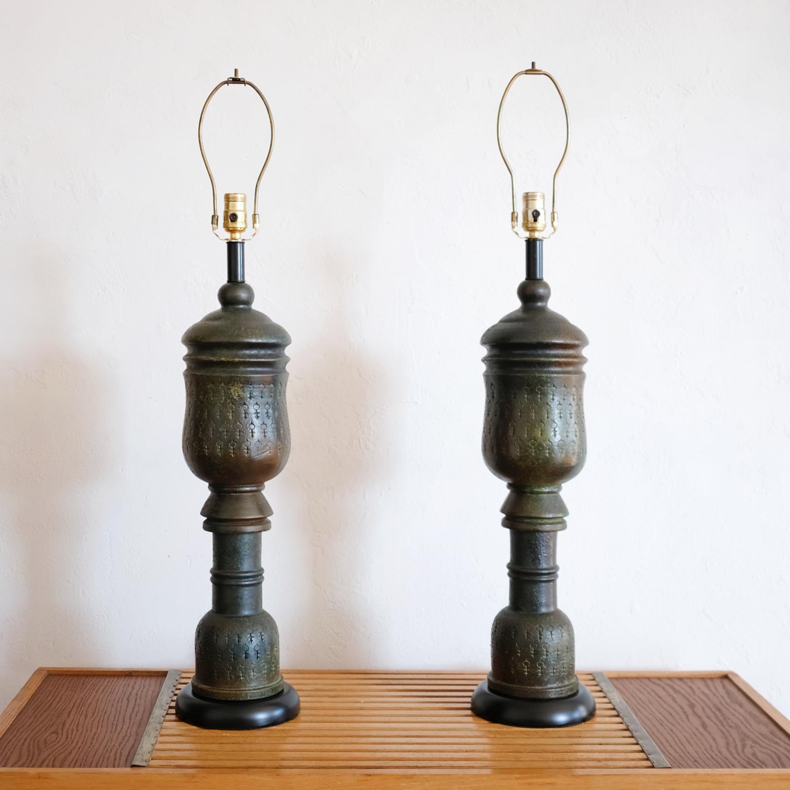 A pair of ceramic lamps by Bitossi. The glaze has an incredible rich patina look. There is an incised symbols repeated around the circumference of two sections. Wood bases. Shades are not included. Made in Italy, 1960.
