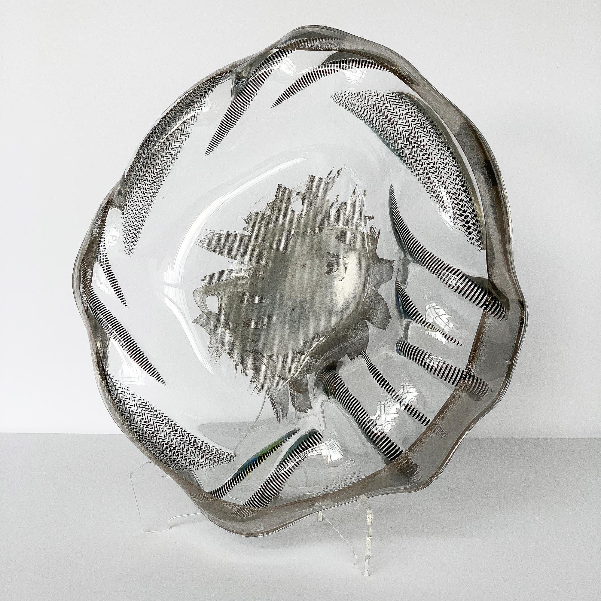 Unique sculptural art glass low bowl with silver details. Textural blackened relief of cord and rope design surrounds a flat depression with layered silver brush strokes. Silver banding along entire perimeter of the bowl. Consider displaying on an