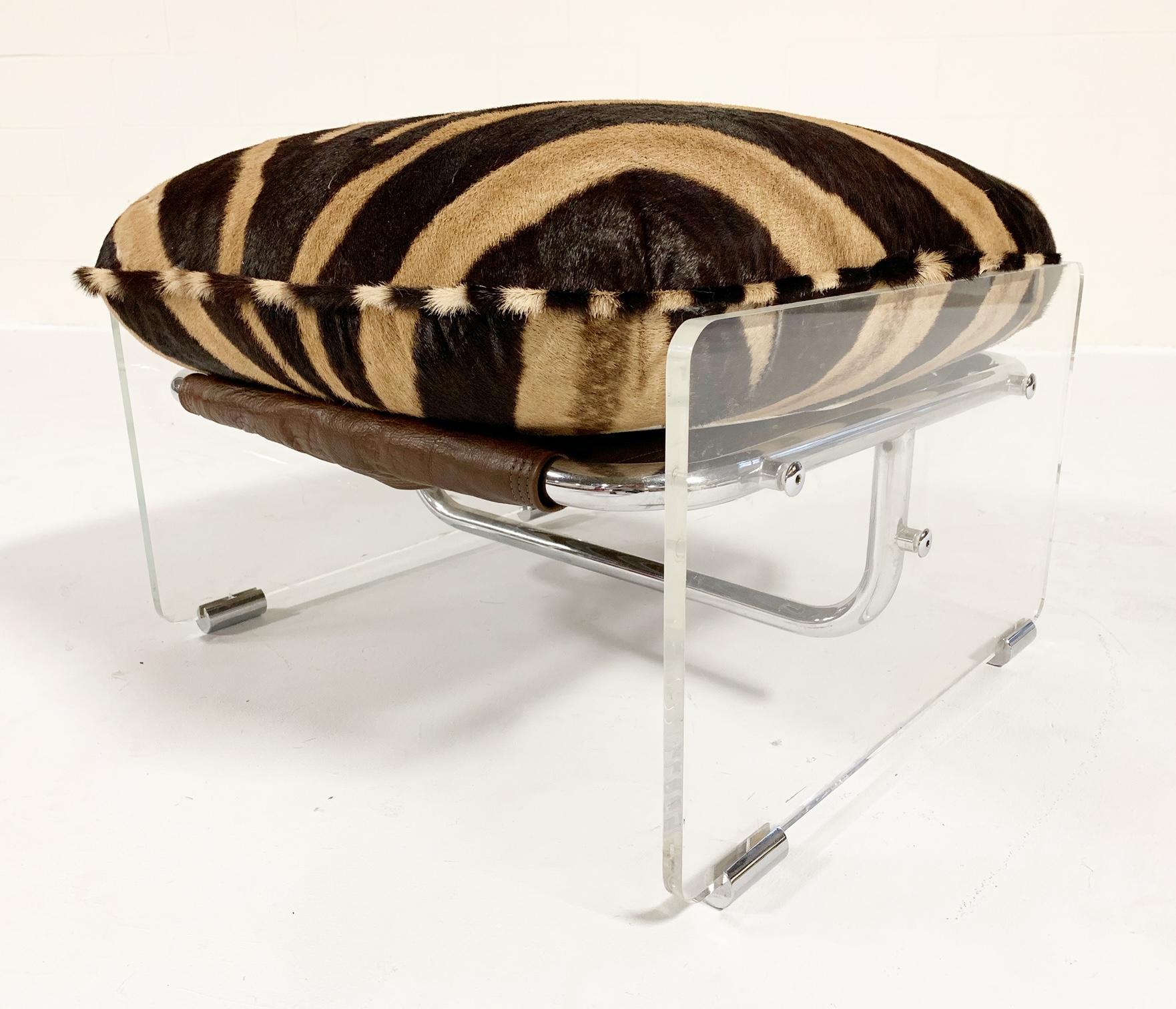 This amazing 1970s Pace Collection lounge chair and ottoman features thick Lucite panels with chrome details. Suede and wool straps wrap the tubular chrome frame to support the cushions. The loose cushions have been masterfully upholstered in zebra