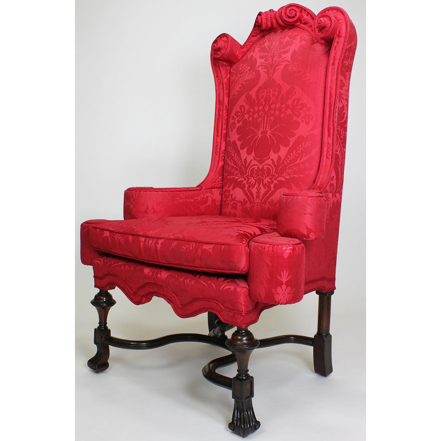 A fine and rare pair of English 19th century William & Mary style mahogany and silk-upholstered armchairs. The high-back frames with scrolled upholstered corners, rounded armrests with side bumpers all raised on our legs conjoined with a scrolled