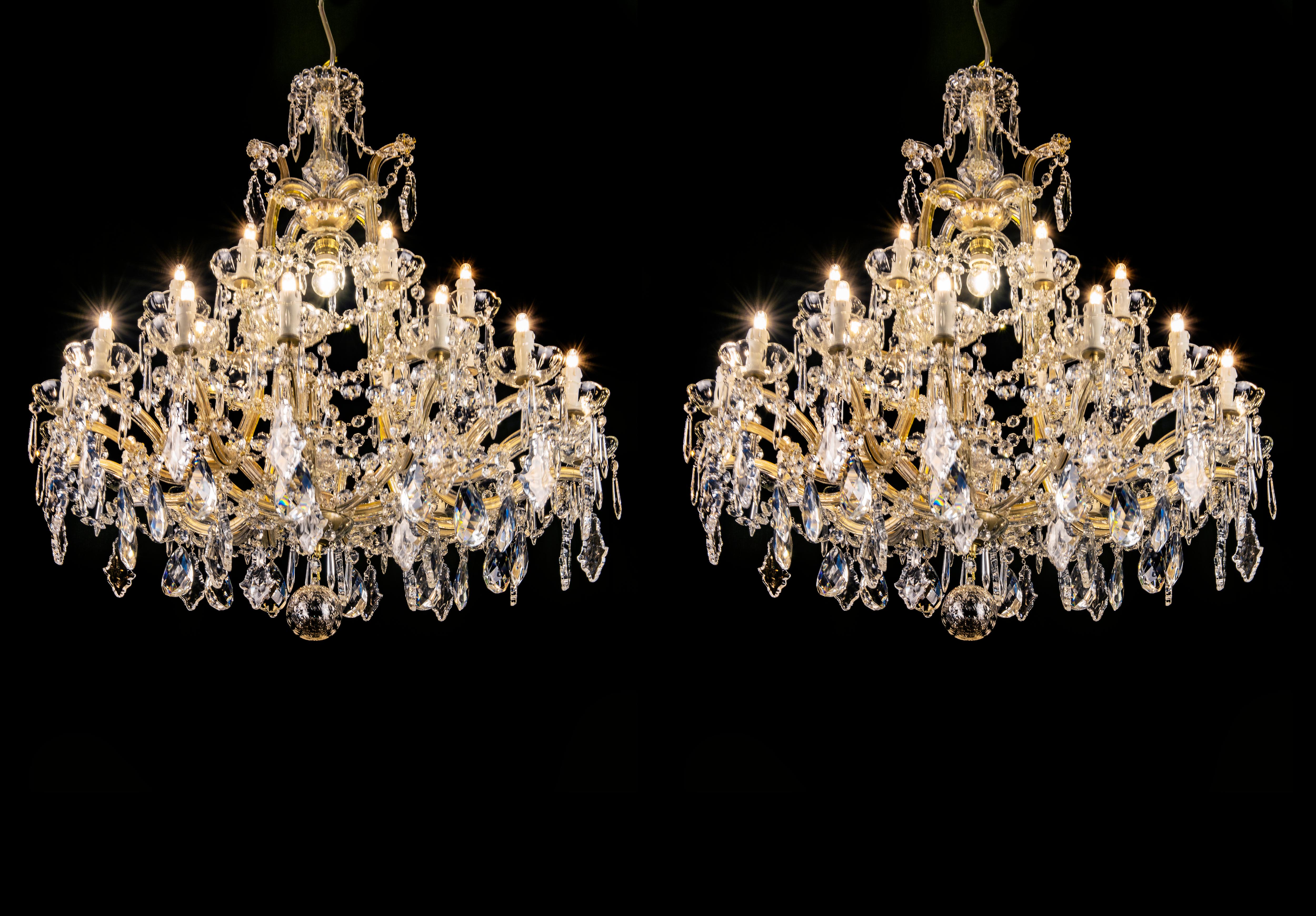 Gorgeous pair of Italian Marie Therese twentyfive light crystal chandeliers with a shaped central stem surmounted by beautifully contoured scrolling arms. These lovely two-tier chandeliers (or hanging fixtures) of crystal, cut-crystal and gilt metal