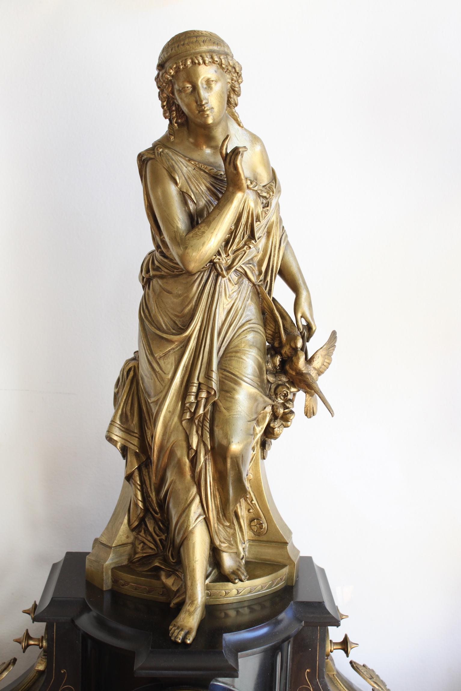 19th century garniture set with clock and candlestick, in marble and bronze, representing an antique woman with birds.
Signed MAGE.
In good state, slight loses and crack on the corner.
Movement in working order.
Dimensions of the two