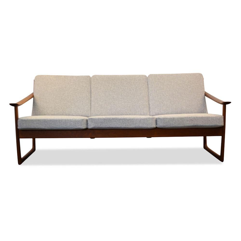 Gorgeous Danish modern FD-130 three-seat sofa designed by top designer duo Peter Hvidt & Orla Mølgaard Nielsen voor France & Son. This rare model FD-130 features a unique sled base design and a solid teak frame. We’ve re-upholstered the sofa in a