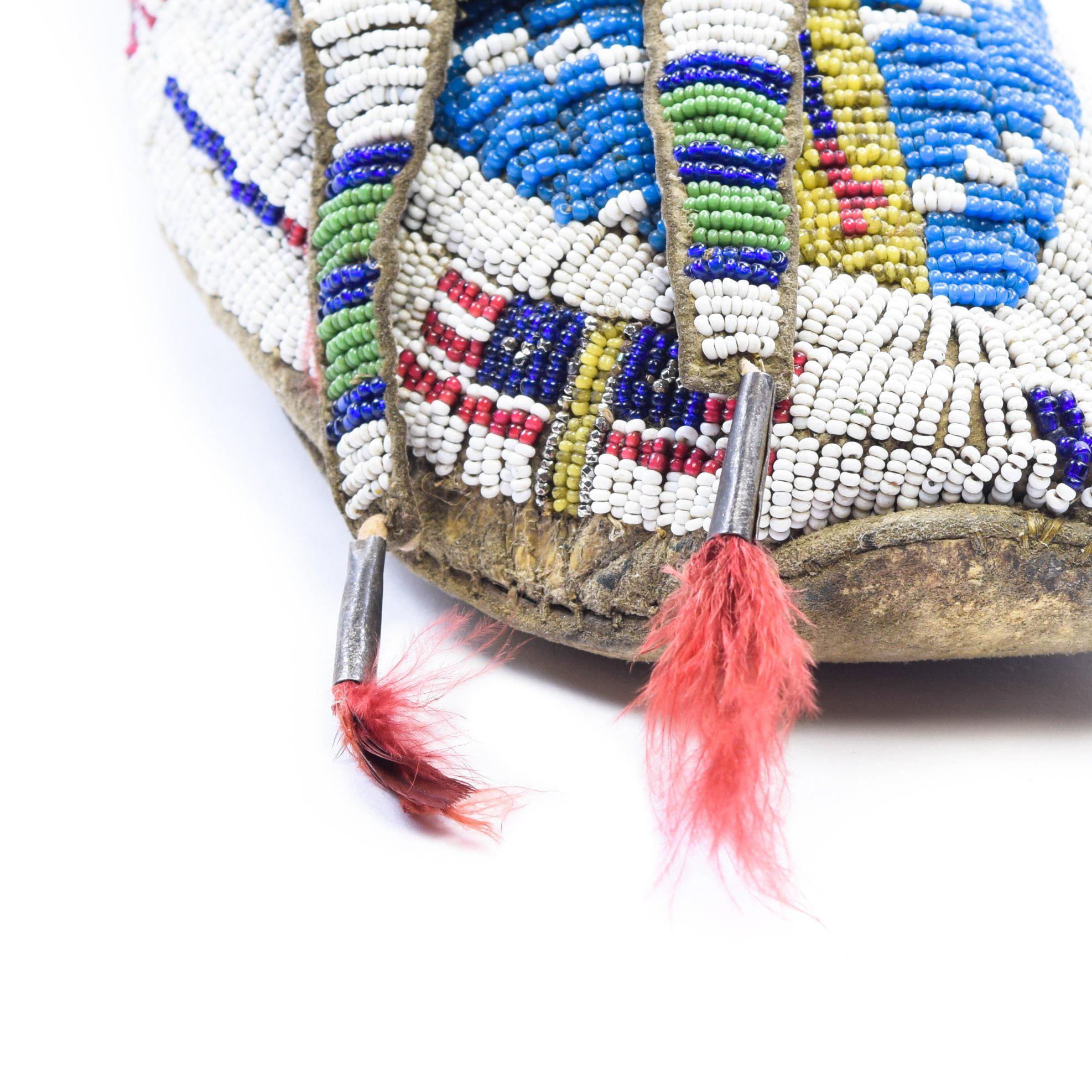 Stunning Sioux moccasins, beaded, primarily in blue and white, with flag motif and horse hair tuffs on tabs.

Period: circa 1880

Origin: Sioux, Plains

Size: 10 3/4