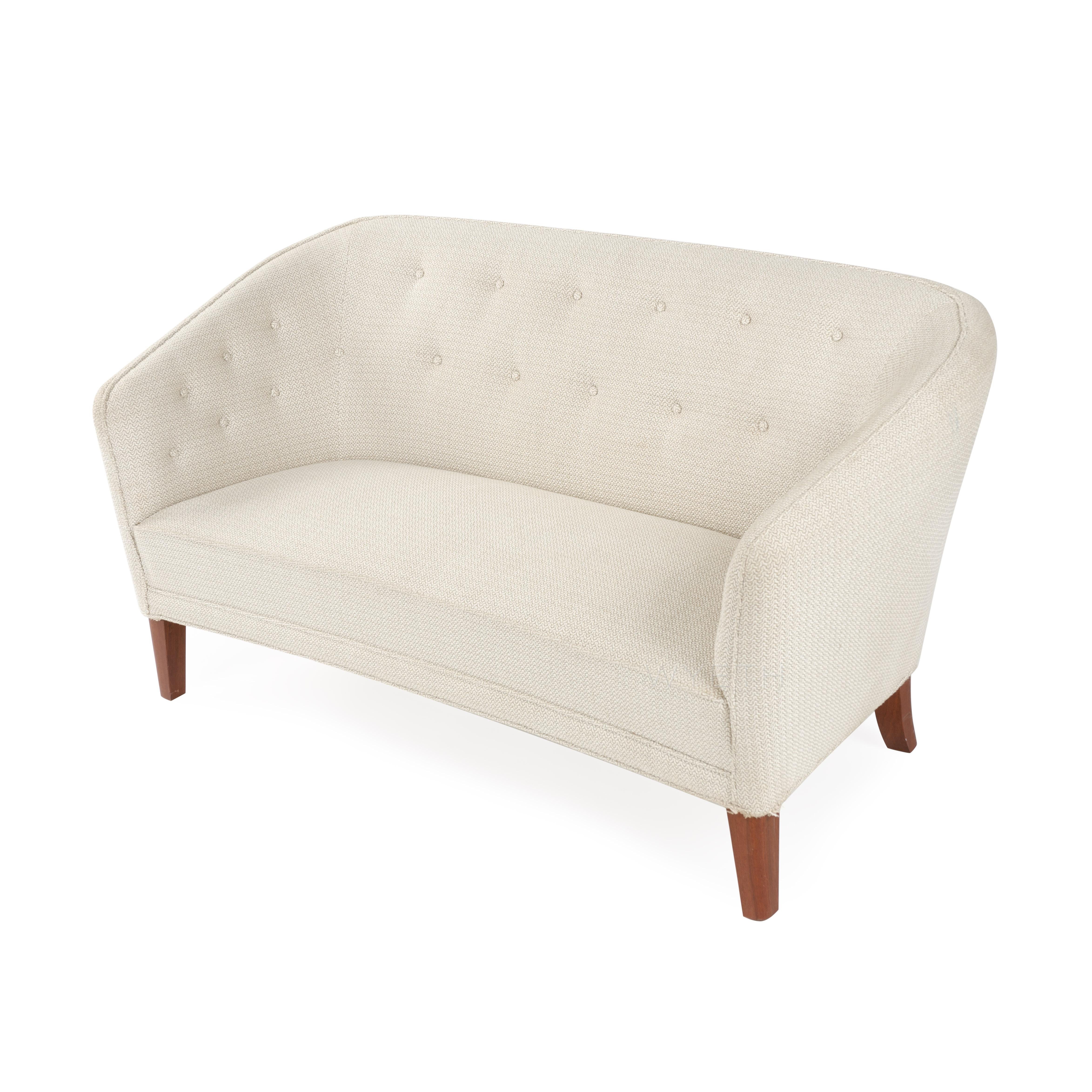 An elegant and superbly crafted high-backed settee having a curving wraparound button-tufted back and tapered dowel-form legs.
