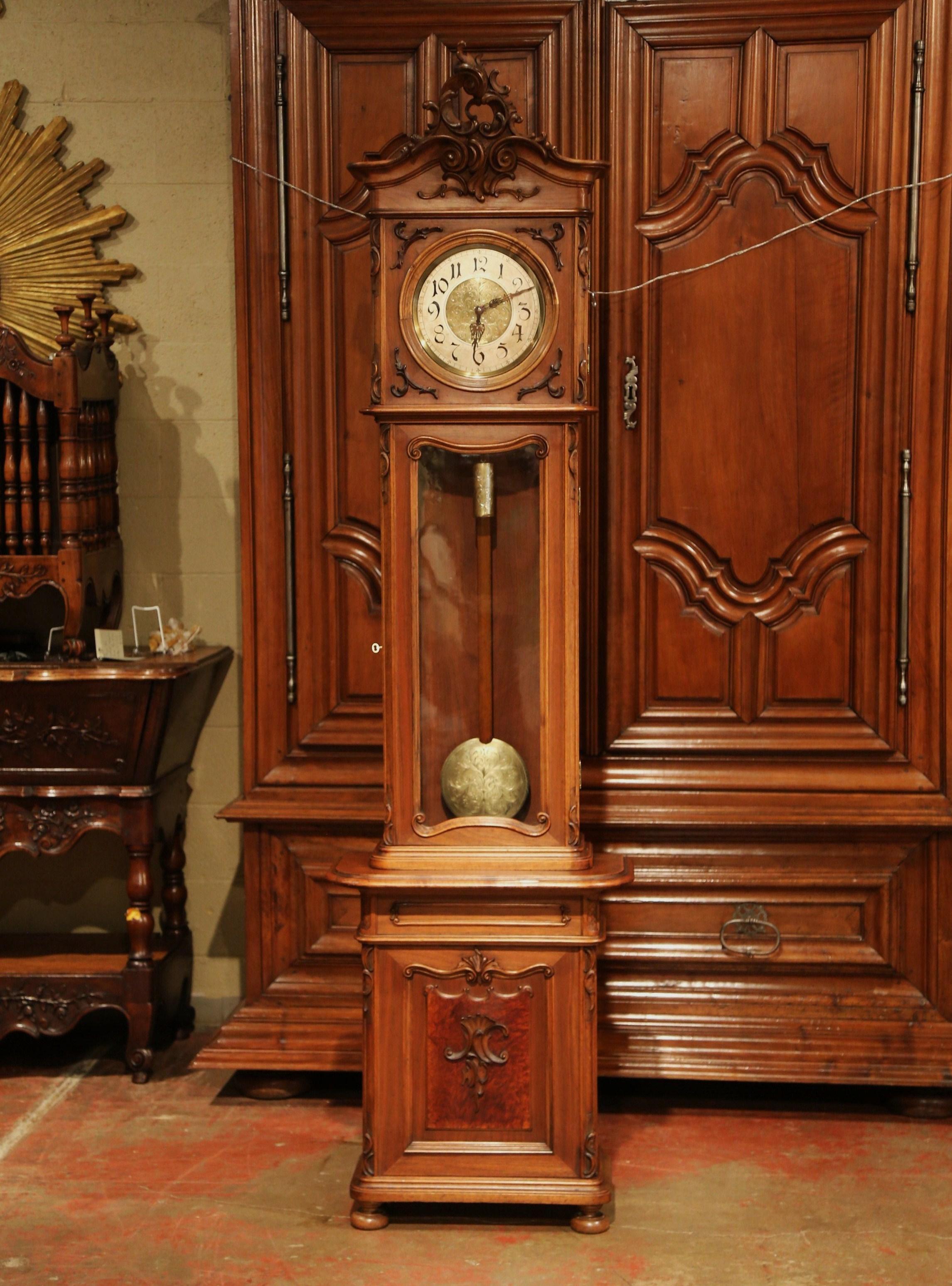 This elegant, antique long case clock was crafted in Lyon, France, circa 1870. The tall fruit wood grandfather clock sits on small round bun feet, and features beautiful carved lines with foliage motif at the pediment, floral and leaf decor on the