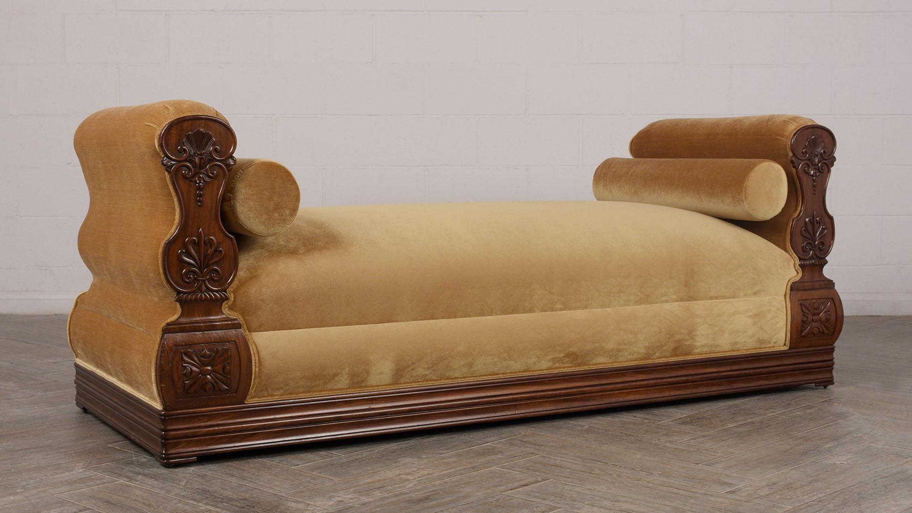 This circa 1840s Regency style daybed features hand carved mahogany wood panels and 4-inch thickness molding around the base original rich dark mahogany finish. The daybed has been newly upholstered in a gold-colored velvet fabric, comes with two