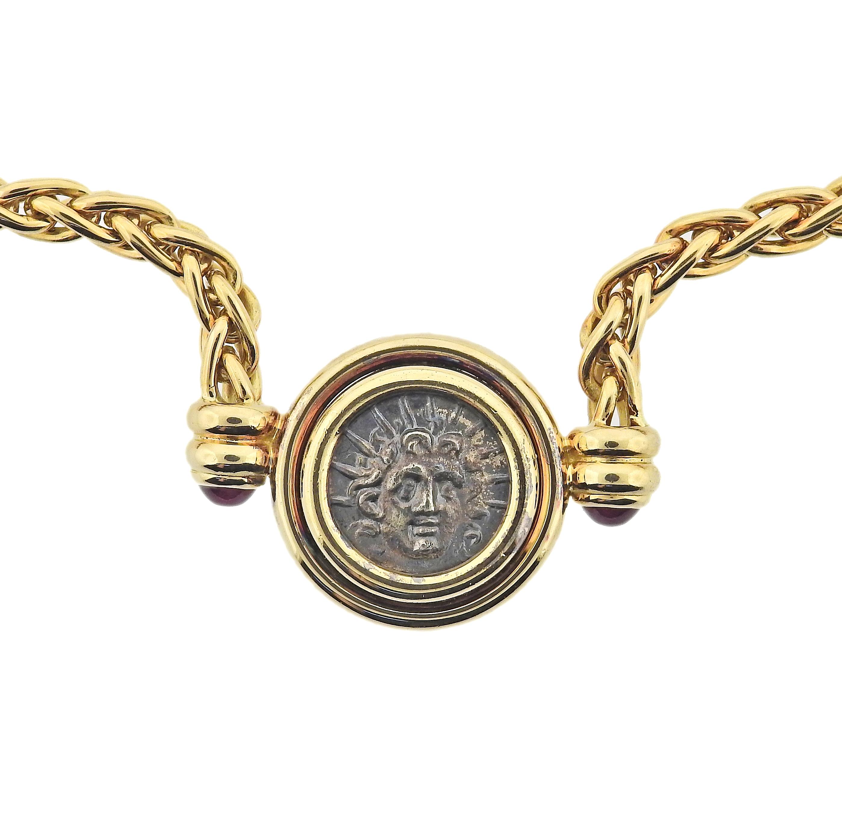 18k gold necklace by Bulgari featuring a bezel set ancient coin and ruby cabochon accents. Necklace measures 15.5 inches long, coin in bezel measures 17mm in diameter. Marked: Caria Rhodos 2 aime siele a.c., Bvlgari 750.