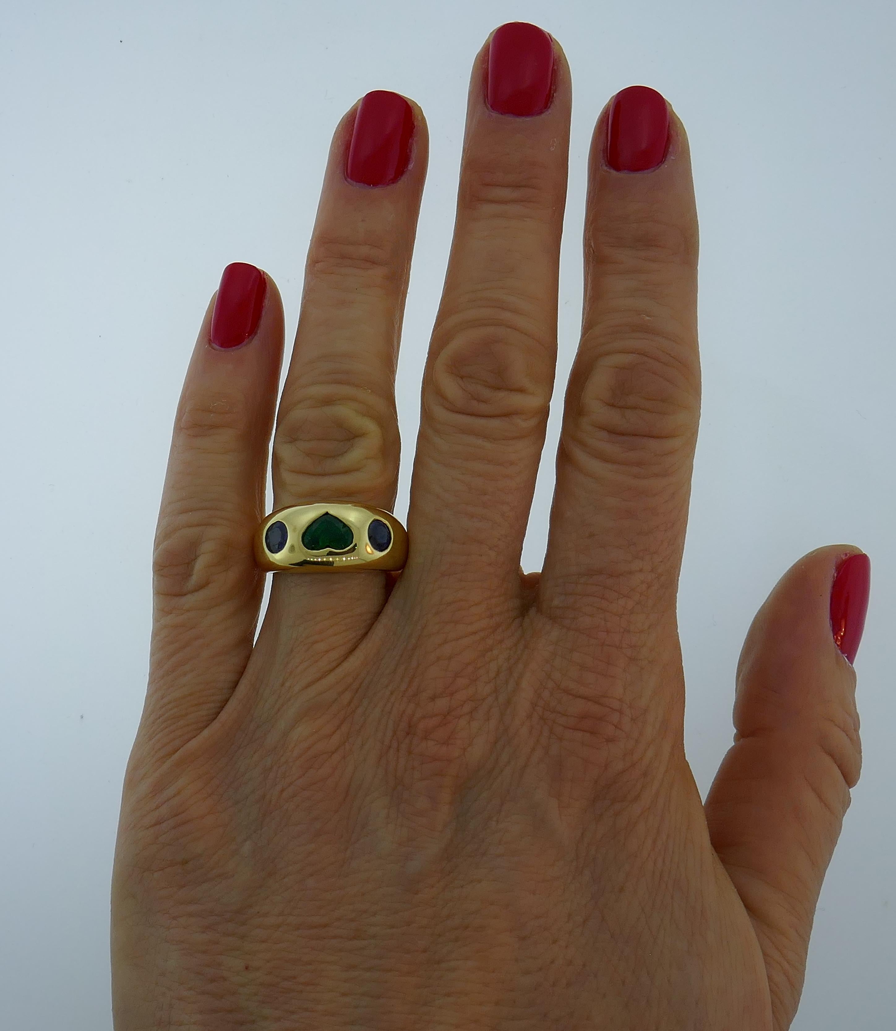 Beautiful ring created by Bulgari in Italy in the 1980s. Features an approximately 1.12-carat heart-shaped faceted emerald set in 18 karat yellow gold and accented with two 0.18-carat each round faceted sapphires. Timeless, classy and wearable, the