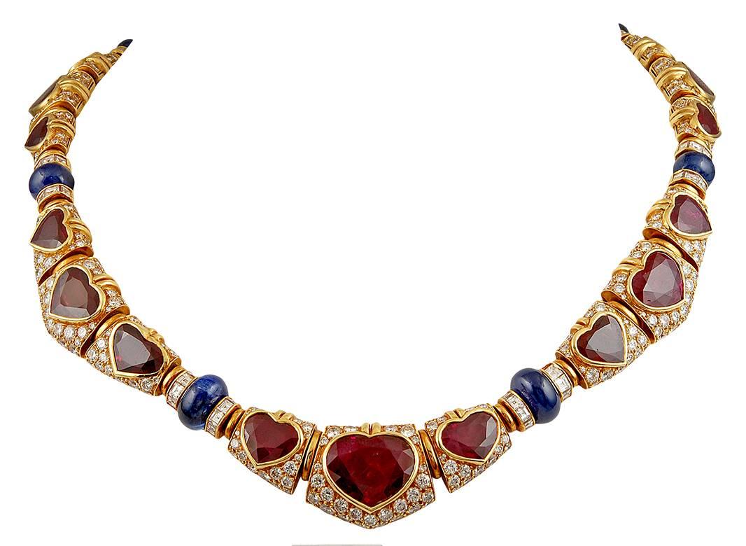 Vintage 18k yellow diamond necklace, designed as a series of links pave-set with brilliant-cut diamonds, set at the center with graduated heart-shaped rubies and cabochon sapphires. The bracelet, earrings and ring of similar design, signed Bvlgari.
