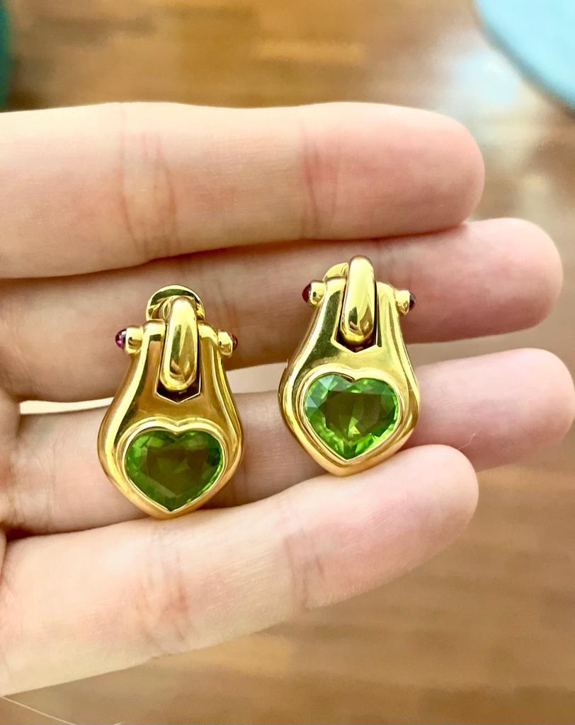 Iconic Bulgari design for these Bold clip on/pin earrings, designed and made in Italy in solid 18k yellow gold, mounting heart-shaped peridots totalling approx. 7,10 ct and cabochon rubies, bearing Bulgari signature and Roman hallmark. Made in