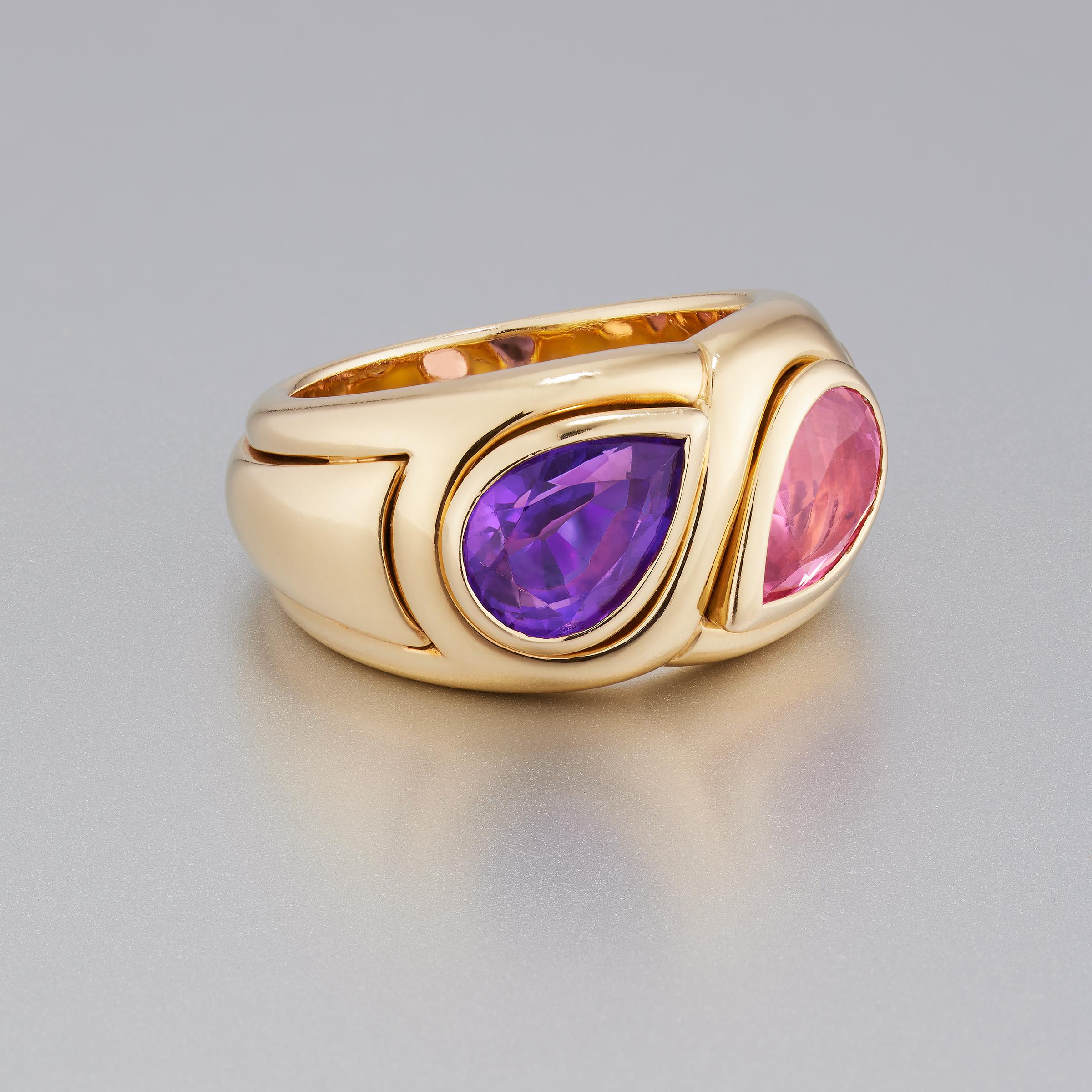 Stylish vintage Bulgari ring features vivid pink tourmaline and purple amethyst gemstones set in 18 karat yellow gold. The two pear-shaped gemstones are facing one another in an elegant ‘Toi et Moi’ design enhanced by complementary outlining and