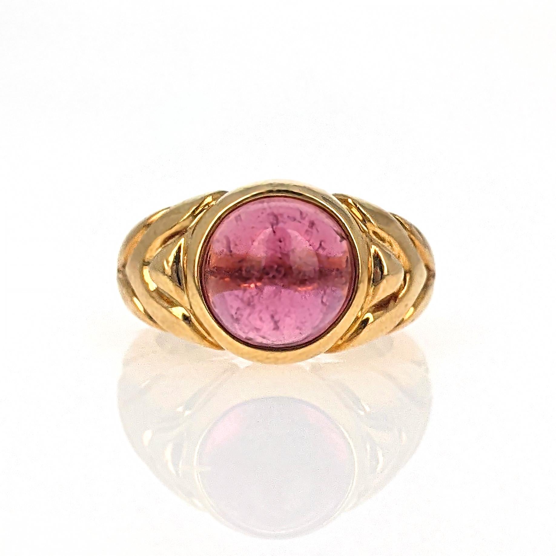 This Bulgari ring centers upon a cabochon pink tourmaline and accented by chevron detailing on the side, mounted in 18 karat yellow gold. It is signed with Italian assay mark. Size 4.75

With original box.