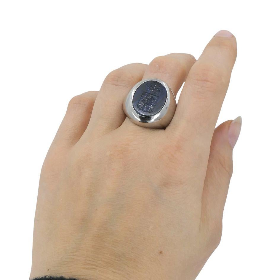 This custom Bvlgari Platinum Sapphire Family Crest Signet Ring combines a timeless design with personal significance. Crafted in platinum, the ring weighs 68.9 grams and features a smooth, polished band that transitions into a bold oval face. The