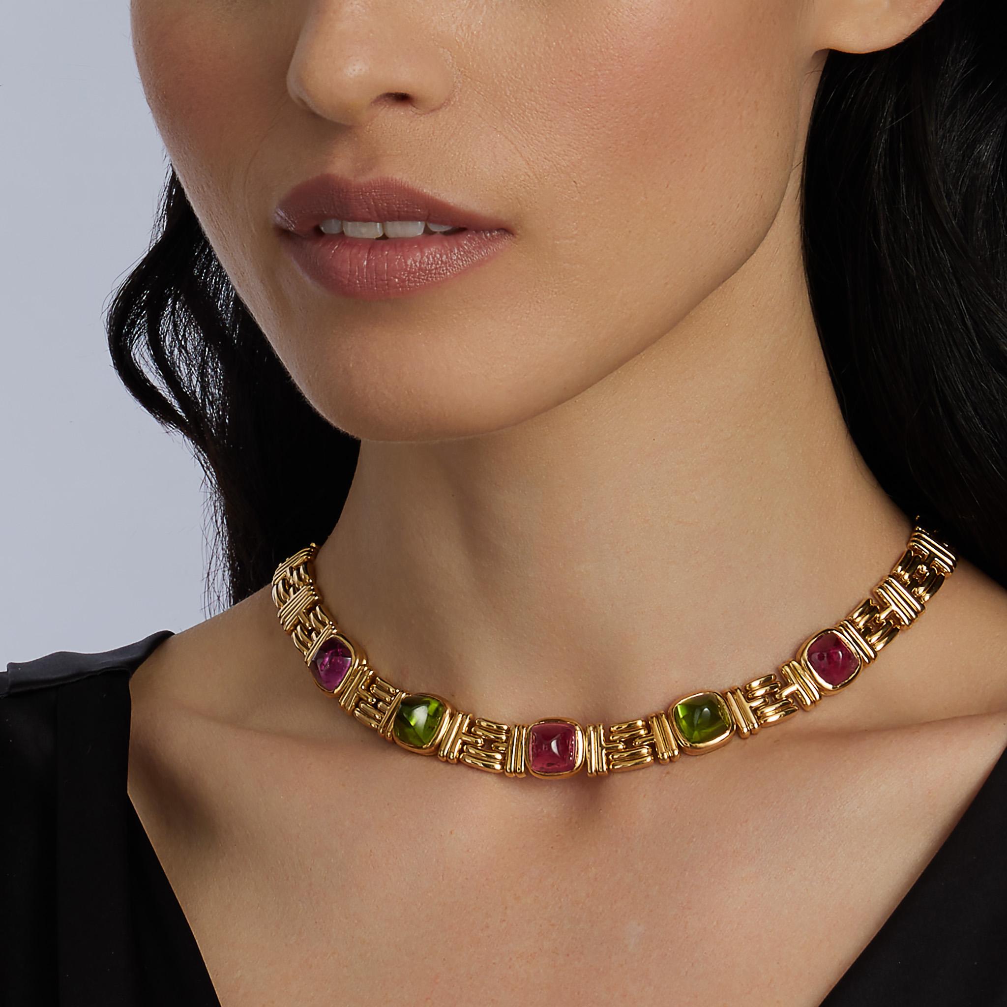 Dieses Collier aus 18 Karat Gold stammt aus den 1980er Jahren und ist mit rosa Turmalinen und Peridots verziert. Er besteht aus drei rosafarbenen Turmalin- und zwei Peridot-Cabochons in Zuckerhutform, die durch eine Kette mit abwechselnd