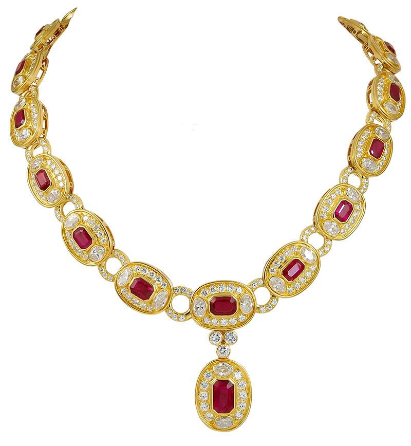 A 1980's Bulgari ruby and diamond necklace and earring suite in 18k gold; the necklace designed as a series of oval-shaped links, each set with a rectangular ruby, two oval diamonds and ten brilliant-cut diamonds, spaced with pave-set diamond hoops.