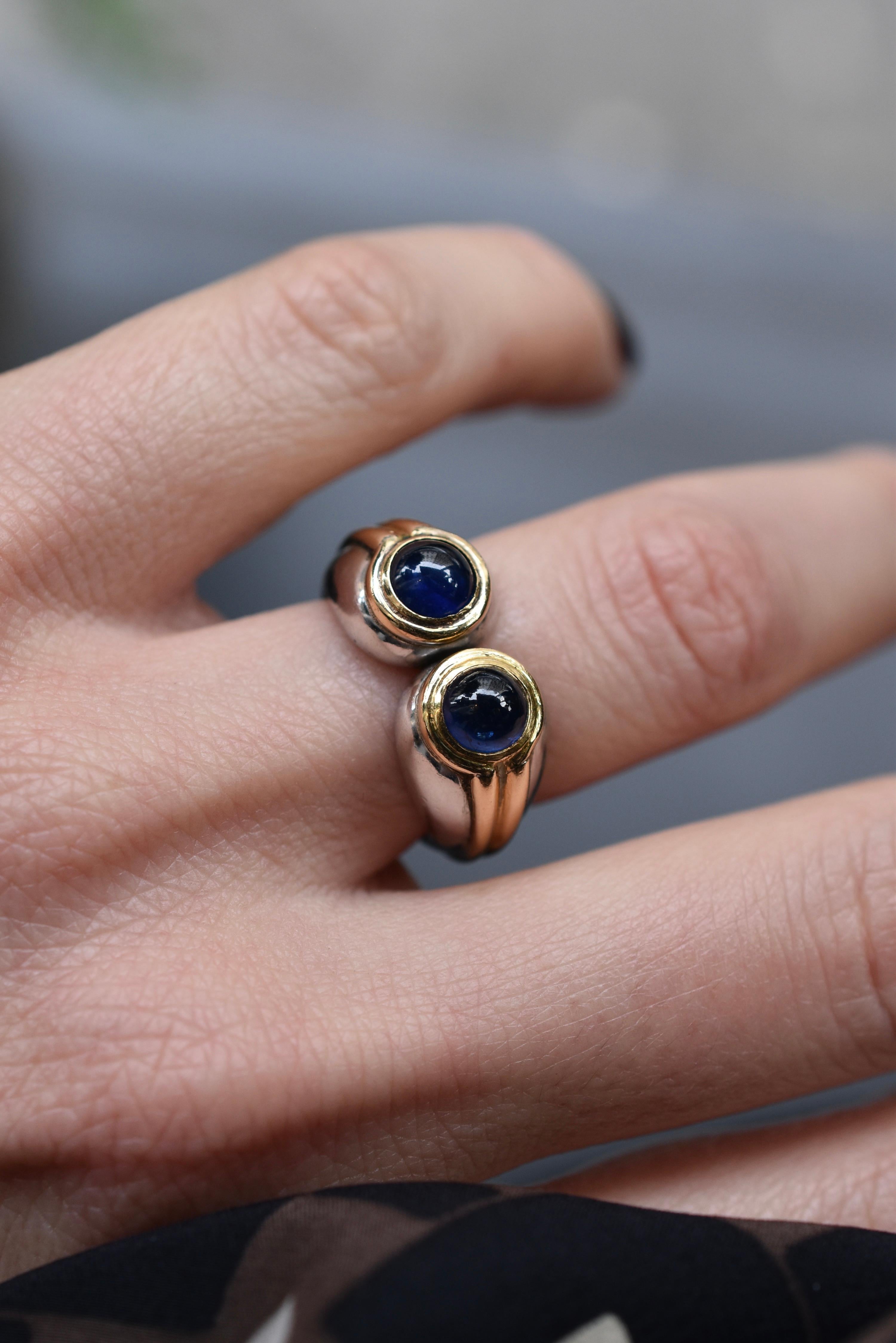 An unusual Bulgari Ring set in a Classic French Style with Platinum and 18k Yellow Gold with two Cabochon-cut Sapphires. Made in Italy, circa 1980. 

The ring is currently a US size 5 3/4.