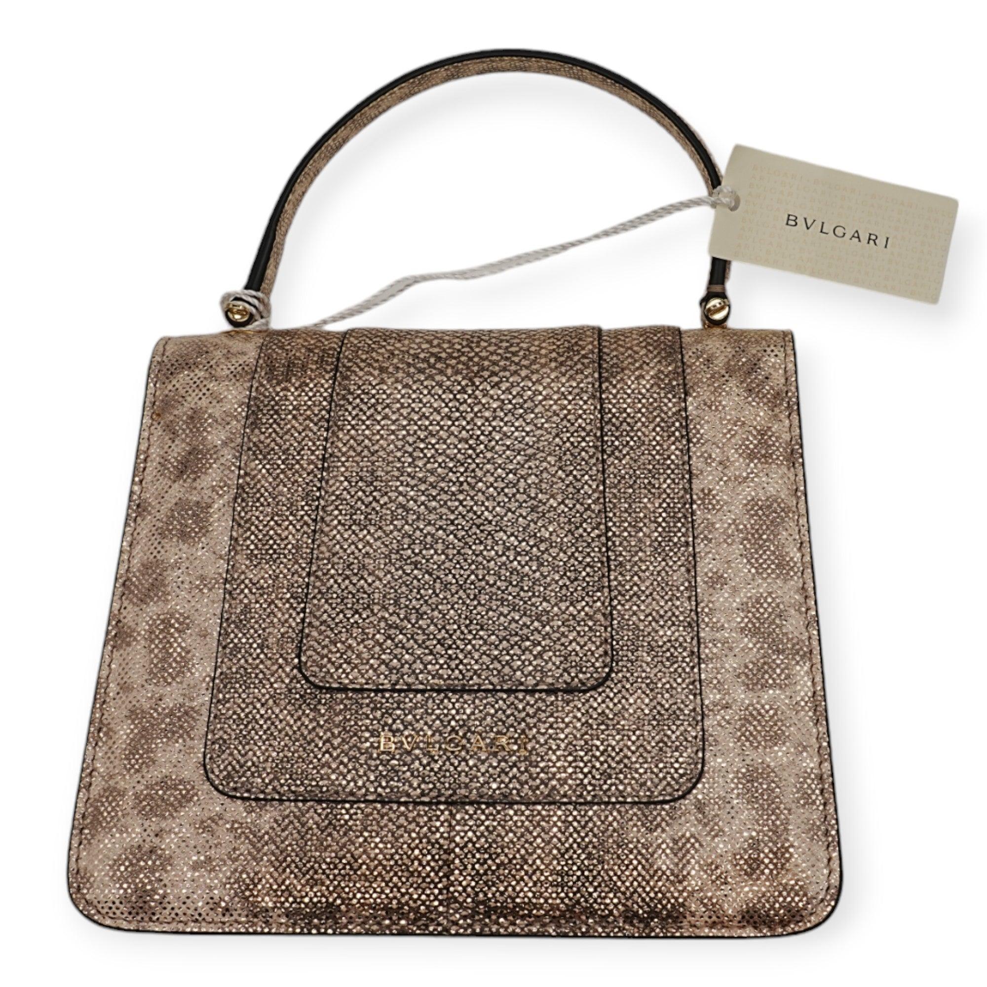 The Serpenti Forever small top handle bag showcases exquisite craftsmanship with its hand-crafted and meticulously painted body, crafted from luxurious silver pearled karung skin. This elegant creation seamlessly combines refined materials with
