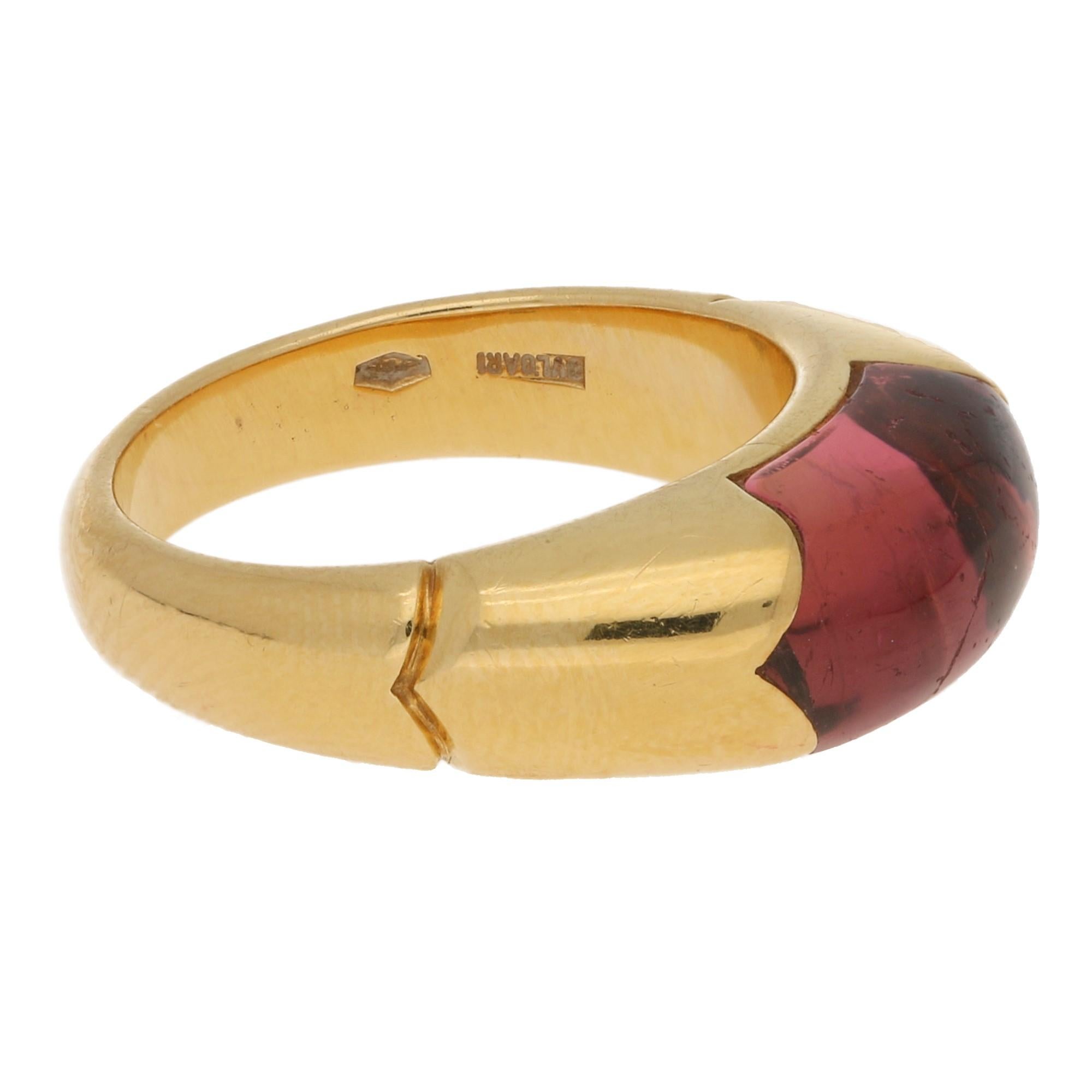 This is a classic original Bvlgari 'Tronchetto' ring featuring a cabochon cut tourmaline beautifully mounted in 18k yellow gold with the well known Bvlagri detailing to each side of the band. 

Finger size UK, K 1/2 , US 5.5 to 6.