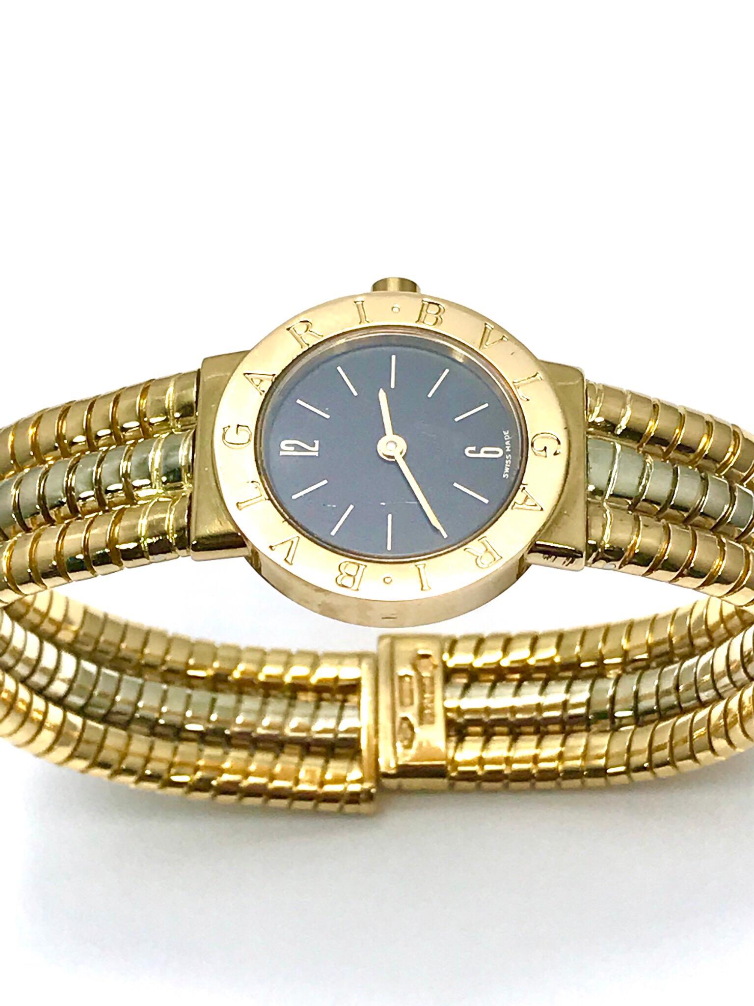 An easy to slip on Bulgari tubogas 18 kaart yellow, rose, and white gold open flex watch bangle bracelet.  The watch dial features arabic numerals at 12 and 6, with index markers as the other hour indicators.  The bezel is engraved with 