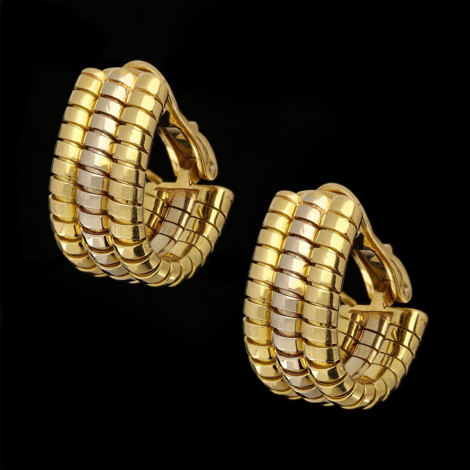 A stylish pair of Vintage Tubogas earrings by Bulgari c.1980s, the wide flat hoop style earrings in 18ct yellow and white gold formed of three rows which curl under and hug the ear, the outer two are yellow gold and the inner one white all with the