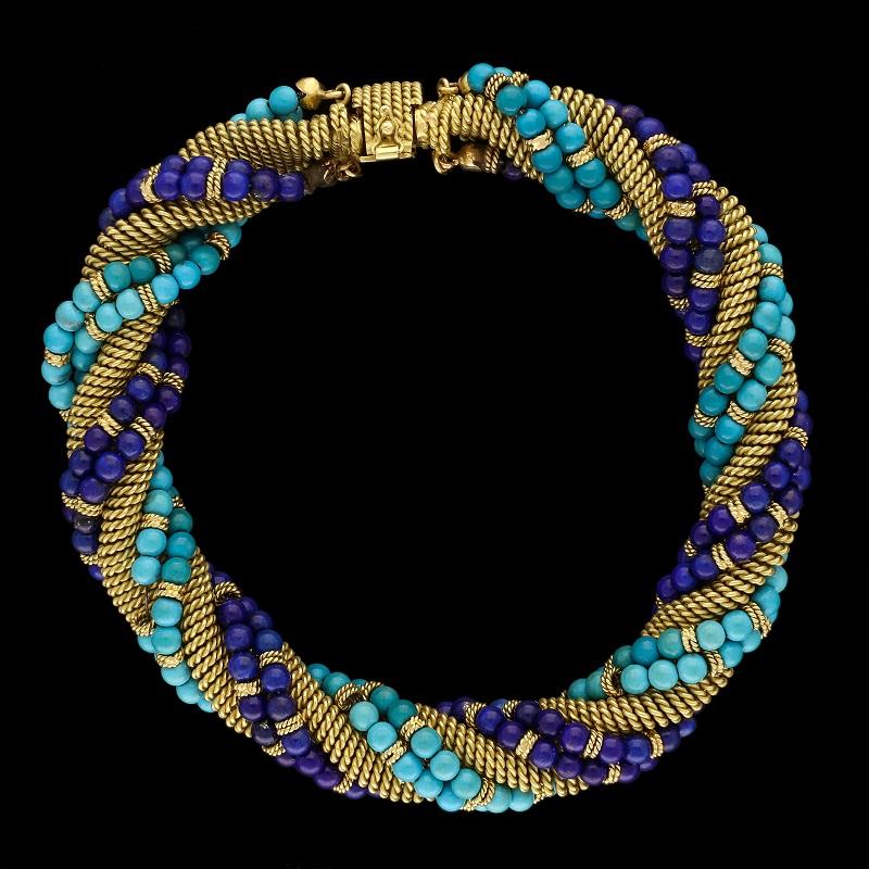 An unusual gold, turquoise and lapis lazuli bracelet by Bulgari c.1960, the bracelet formed of a woven gold strap twisted around and wrapped with a double row of round polished turquoise beads and another of matching lapis lazuli beads, the rows of