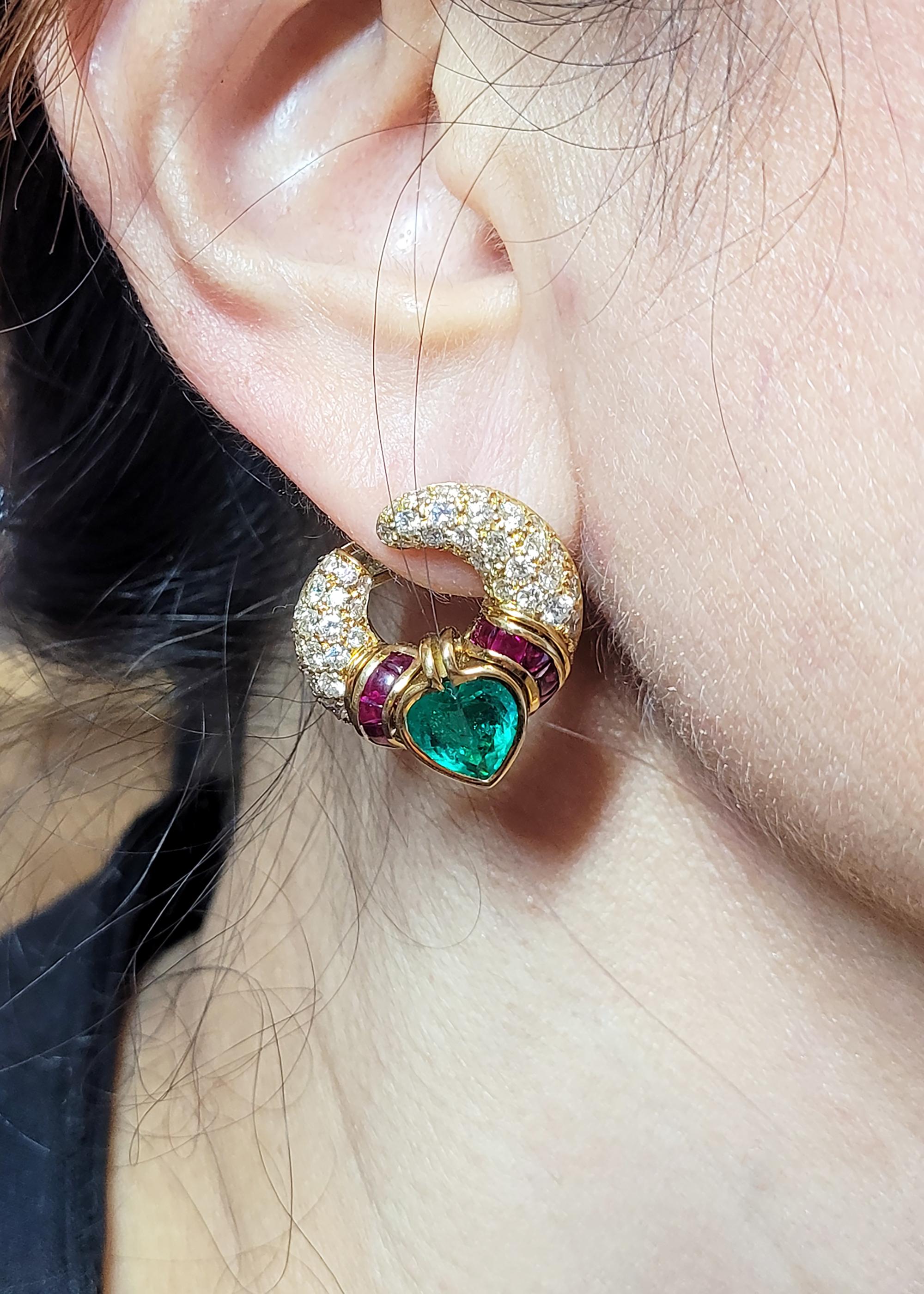 Ein Paar Vintage-Ohrringe von Bvlgari aus den 1980er Jahren.
Bestehend aus zwei kolumbianischen Smaragden in Herzform mit einem Gewicht von 1,81 Karat und 2,04 Karat. 
Akzentuiert durch unsichtbar gefasste Rubine und weiße Diamanten. 
Metall ist 18k