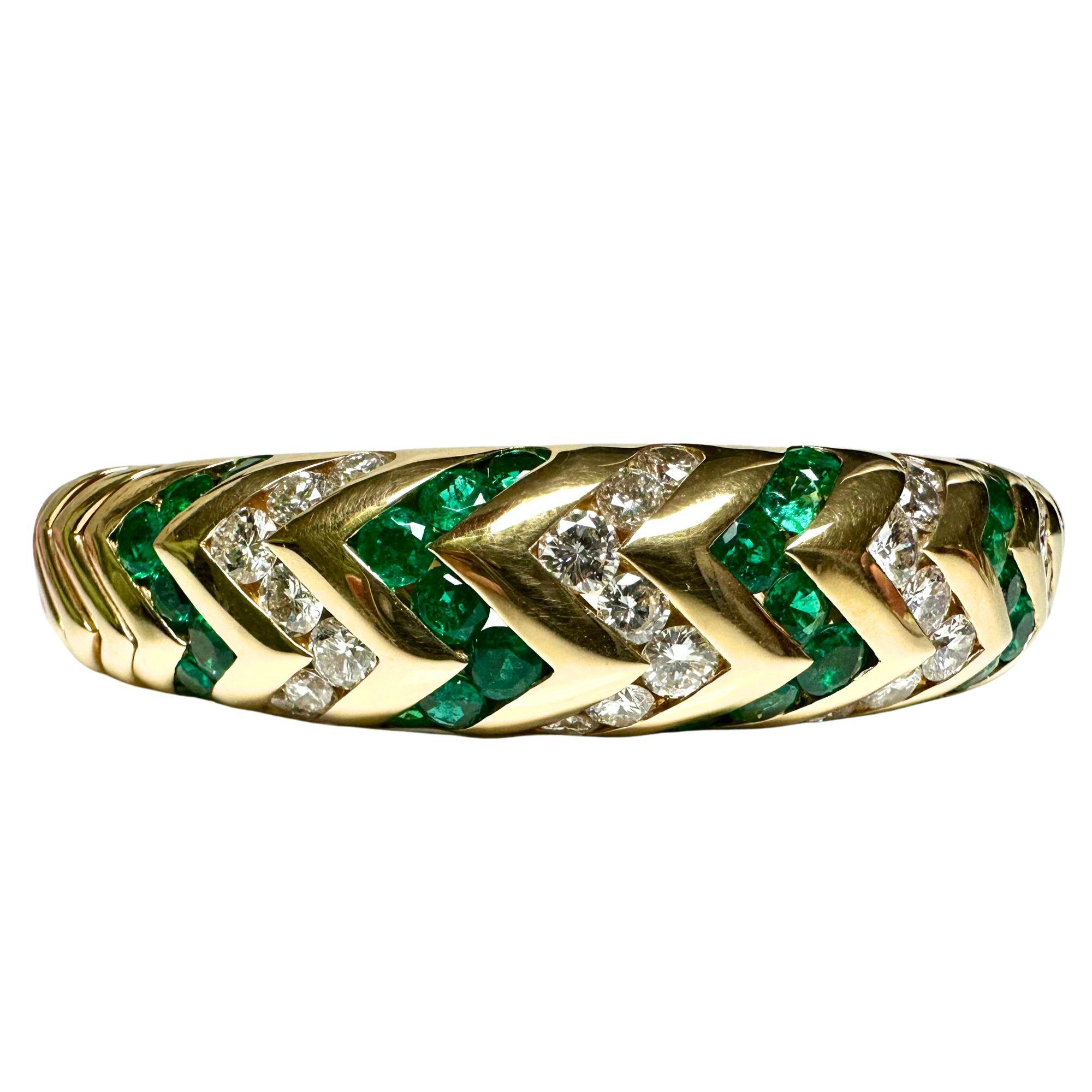A collectible 18k yellow gold expandable cuff highlighted by about 5 carats each of vivid emeralds and bright diamonds made in the early 1970’s. The diamonds are round brilliant-cut and the emeralds are ovals. The yellow gold is sculptured to appear