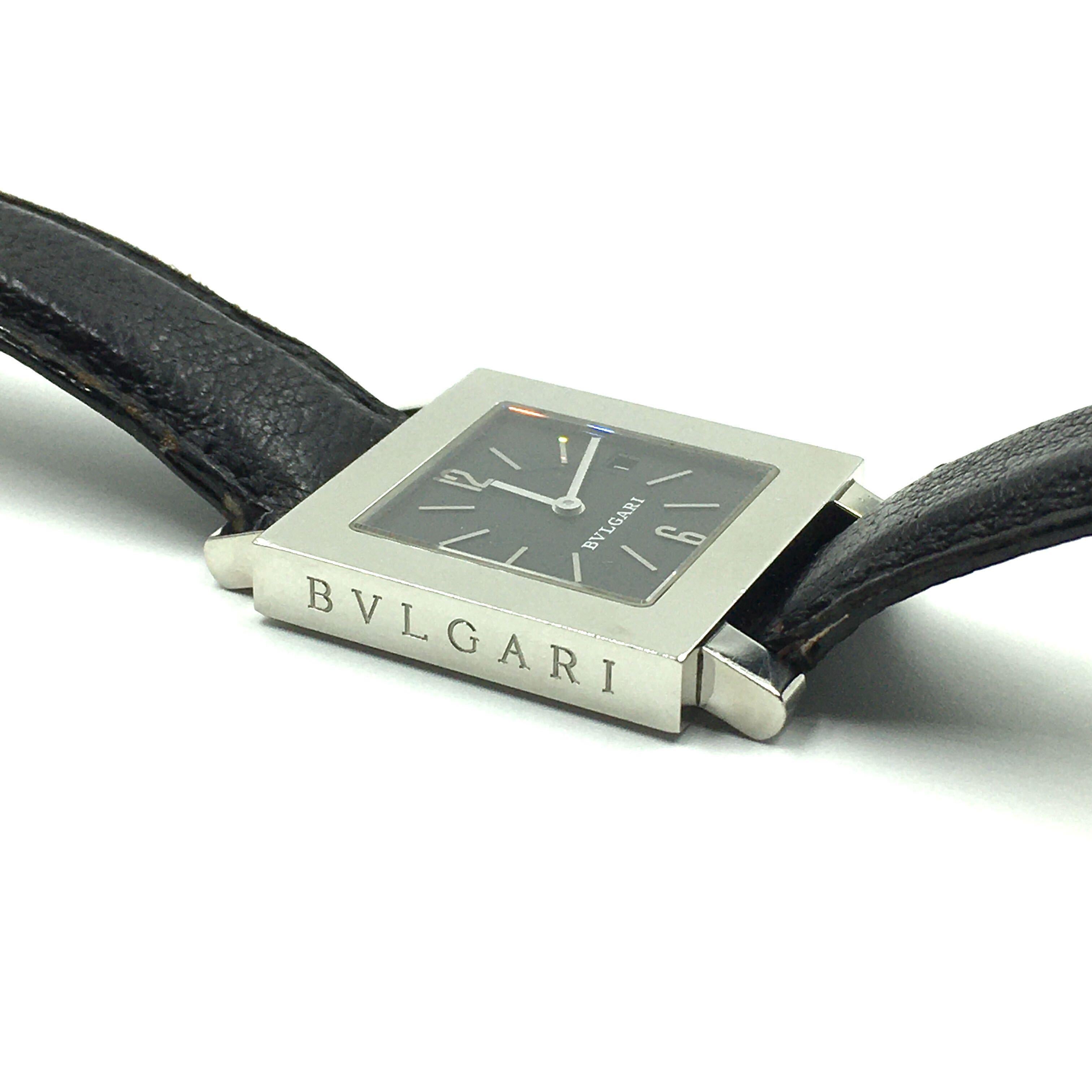 A stainless steel Quadrato watch. Bulgari. 29 mm. Of quartz movement. The black dial of square outline with baton numerals, and Arabic 12 and 6, aperture for date at 3 o’clock, within a polished square stainless steel bezel, joined by a black