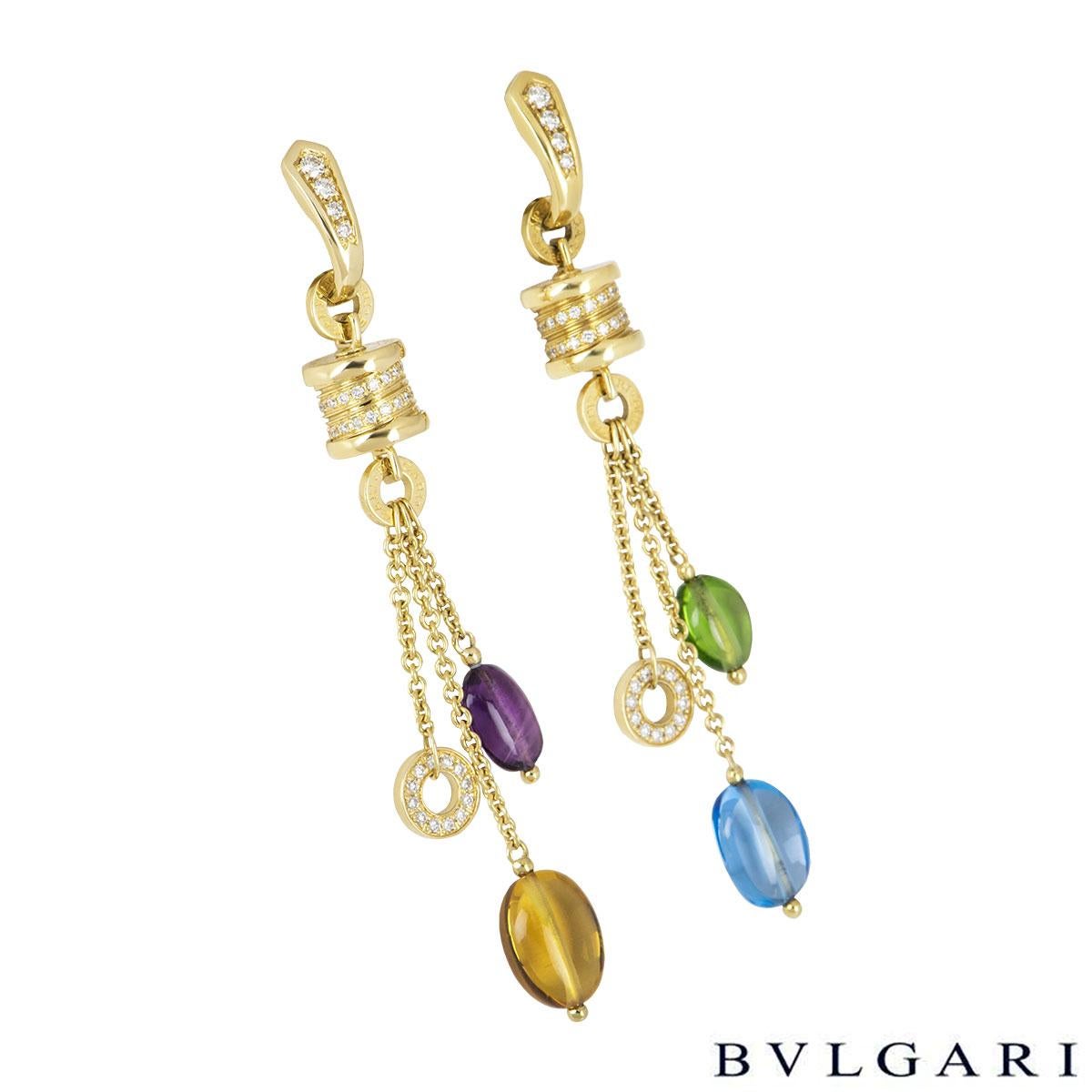 An 18k yellow gold pair of multi-gem earrings by Bvlgari from the B.zero1 collection. The earrings each comprise of the iconic Bvlgari drum partially set with pave round brilliant cut diamonds. Suspended from the barrel are 3 tassels one with the an