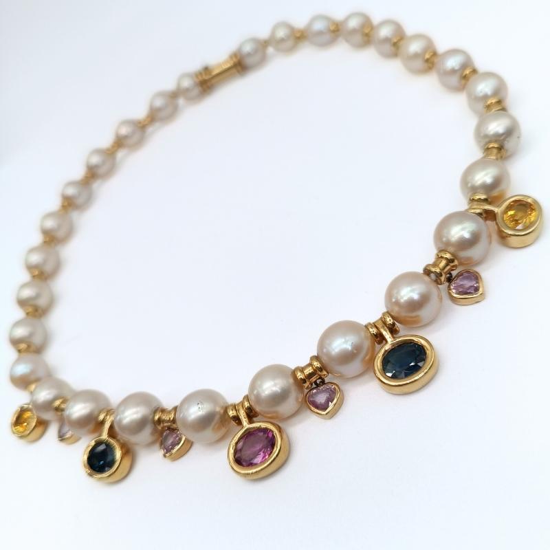  28 separate Akollas pearls with yellow gold ornaments. 4 yellow, blue and pink oval-cut sapphires set in yellow gold. 4 pink heart-shaped sapphires set in yellow gold.

18k yellow gold
28 Akolla perls 9,5/10mm
5 Sapphires: 1 Pink, 2 Blue, 2 Yelow