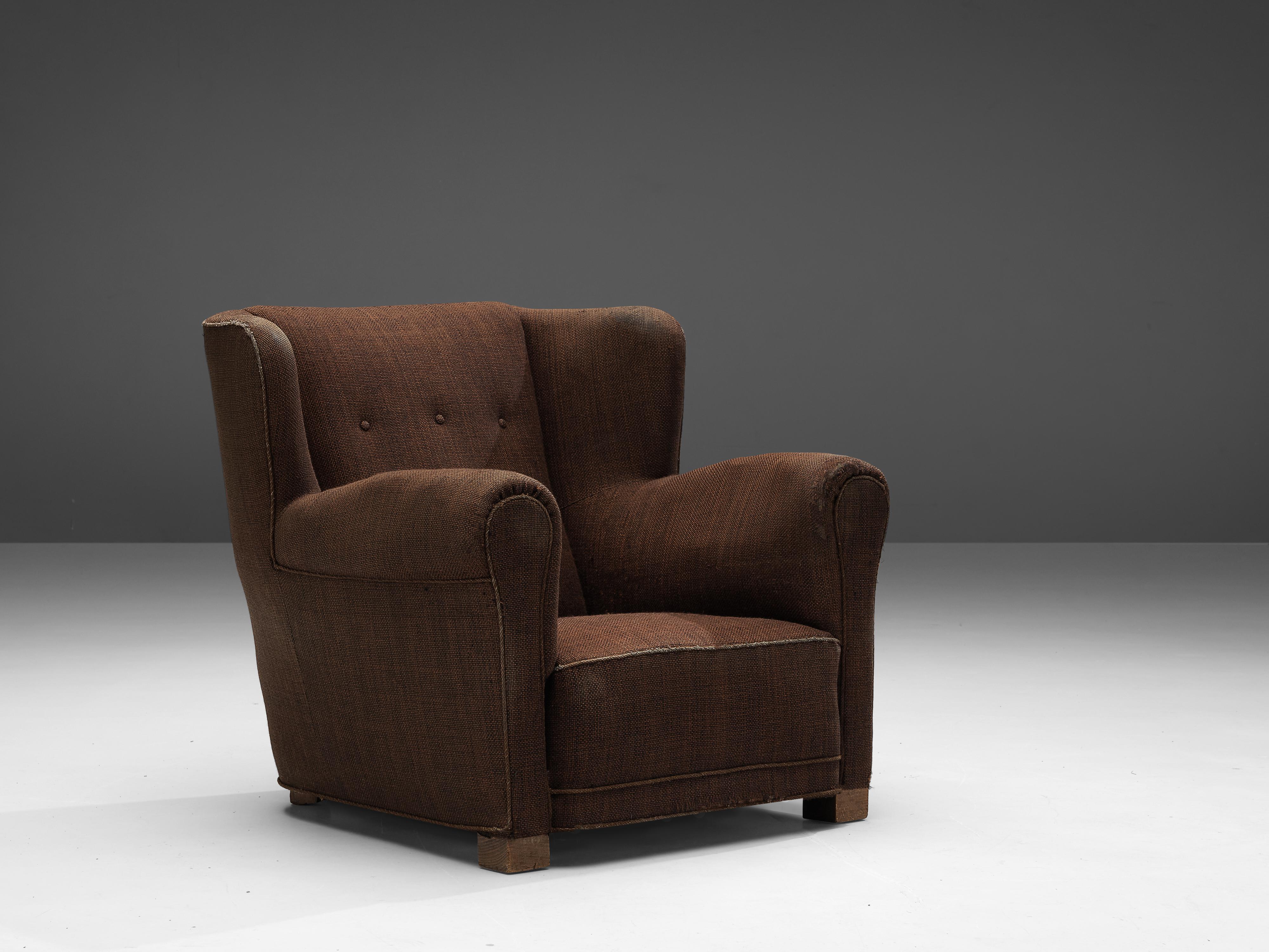 Fauteuil, bois, tissu, Danemark, années 1950

Ce fauteuil volumineux présente un aspect à la fois robuste et accueillant. Le large siège avec accoudoirs et le dossier à ailettes créent une expérience confortable pour l'utilisateur. De dos, la chaise