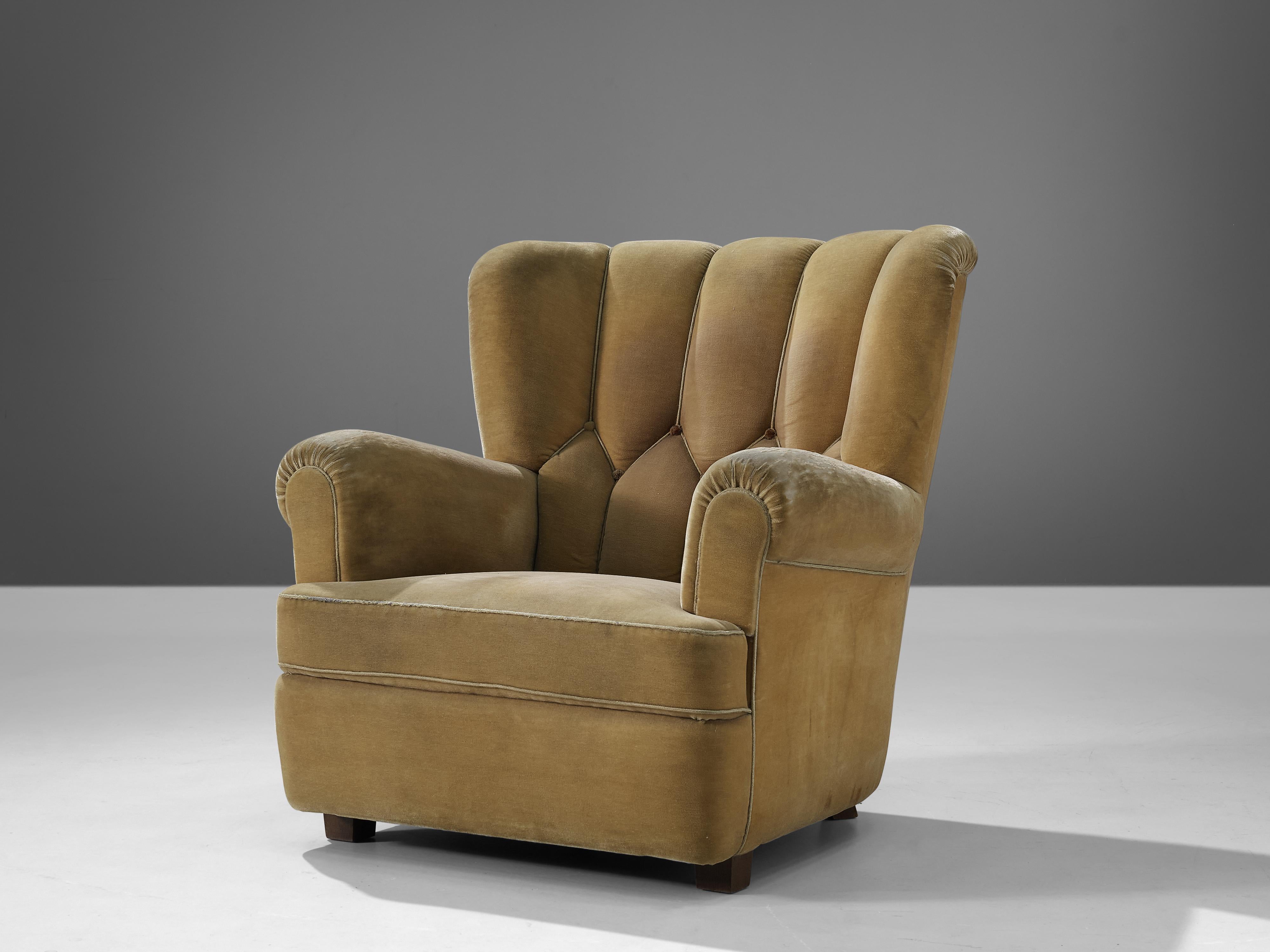 Danish lounge chair, wood, fabric, Denmark, 1950s

This bulky lounge chair features a sturdy yet inviting look. The wide seat with armrests and the backrest with wings, create a comfortable experience for the sitter. From the back, the chair has a