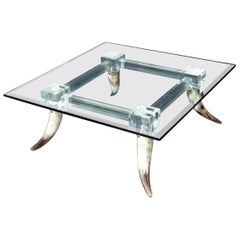 Tavolino da caffè con piano in vetro quadrato con base a forma di corna di toro e gambe in lucite.