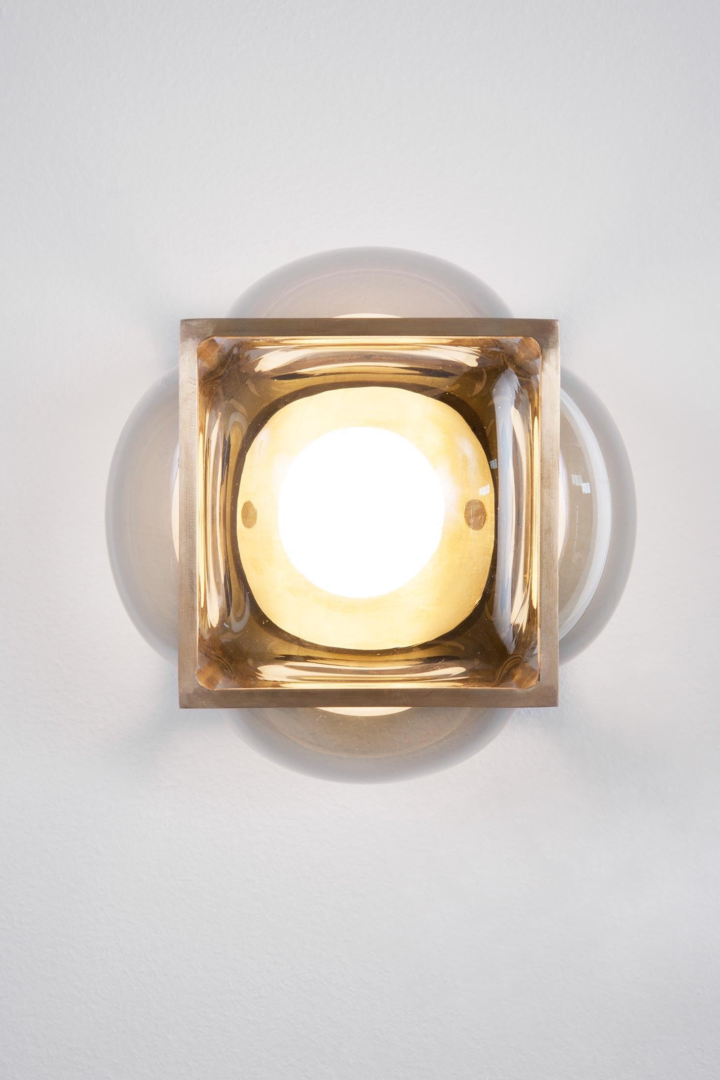 The Bulle can be used as a flushmount or sconce. The glass is hand blown into the solid brass frame. The hand blowed glass is available in either clear grey or opal white. Finish options for the metal frame are either blackened brass or unfinished