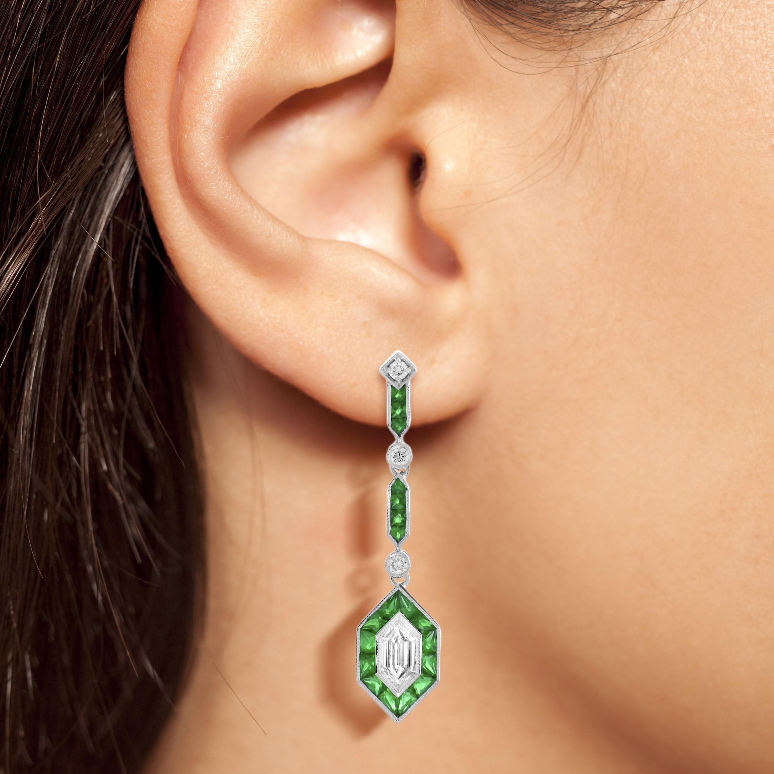 These Art Deco inspired drop earrings features 0.96 carats of total diamonds and 3.75 emerald  finished in a dazzling 18k white gold setting. Both glamorous and imaginative, these drop earrings could be the show stopper addition to your jewelry