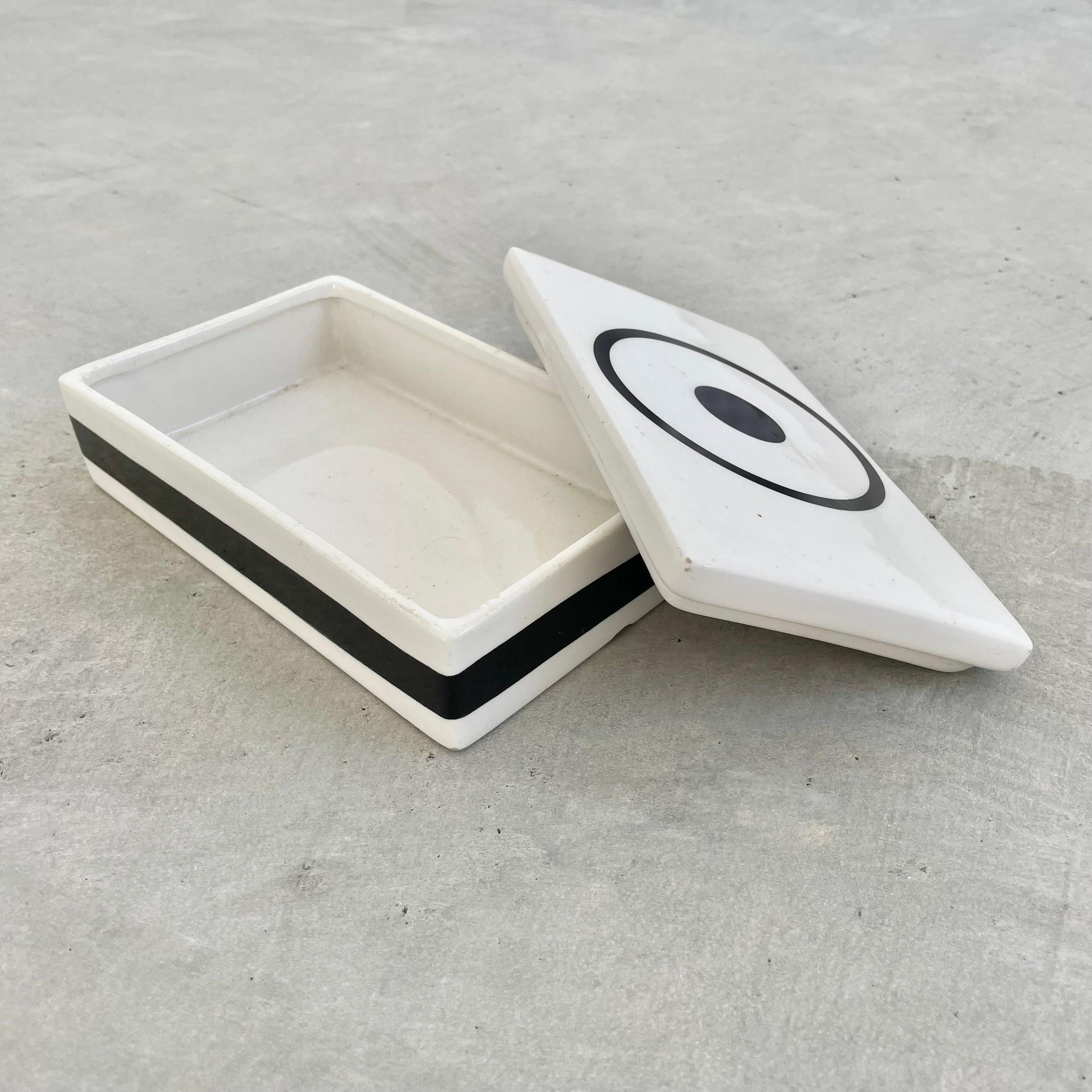 Artsy ceramic box made in Italy, circa 1970s. White box with black Bullseye painted on lid as well as a black stripe that goes around box. Great vintage condition. Fun stash box and tabletop object. Marked Mancioli Made in Italy and Raymor 1404 on