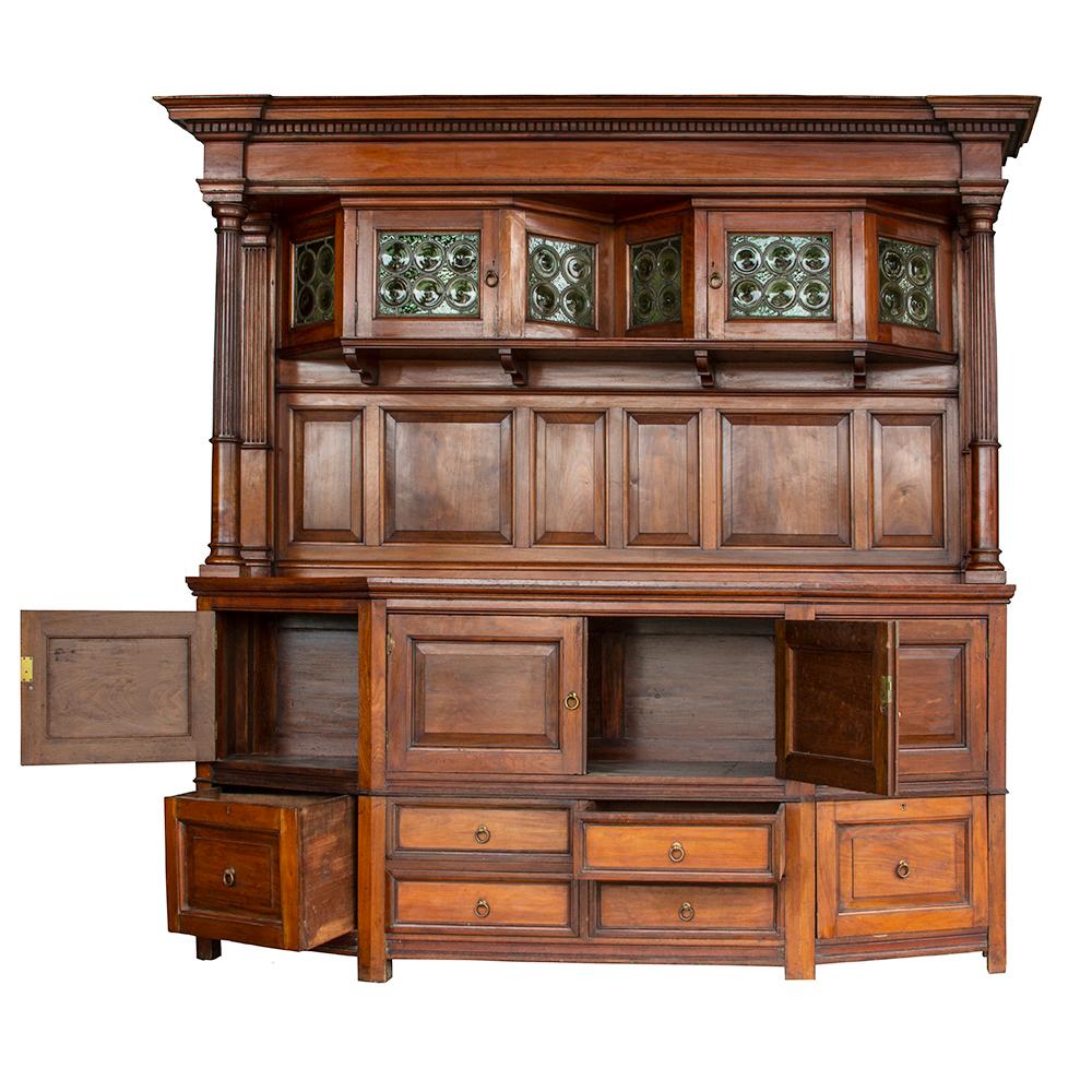 This handsomely solid sideboard is constructed from beautiful solid walnut. The restrained detailing in the delicately reeded columns and dentiled cornice is a subtle contrast to the eye-catching angled upper cabinetry, which is fitted with green