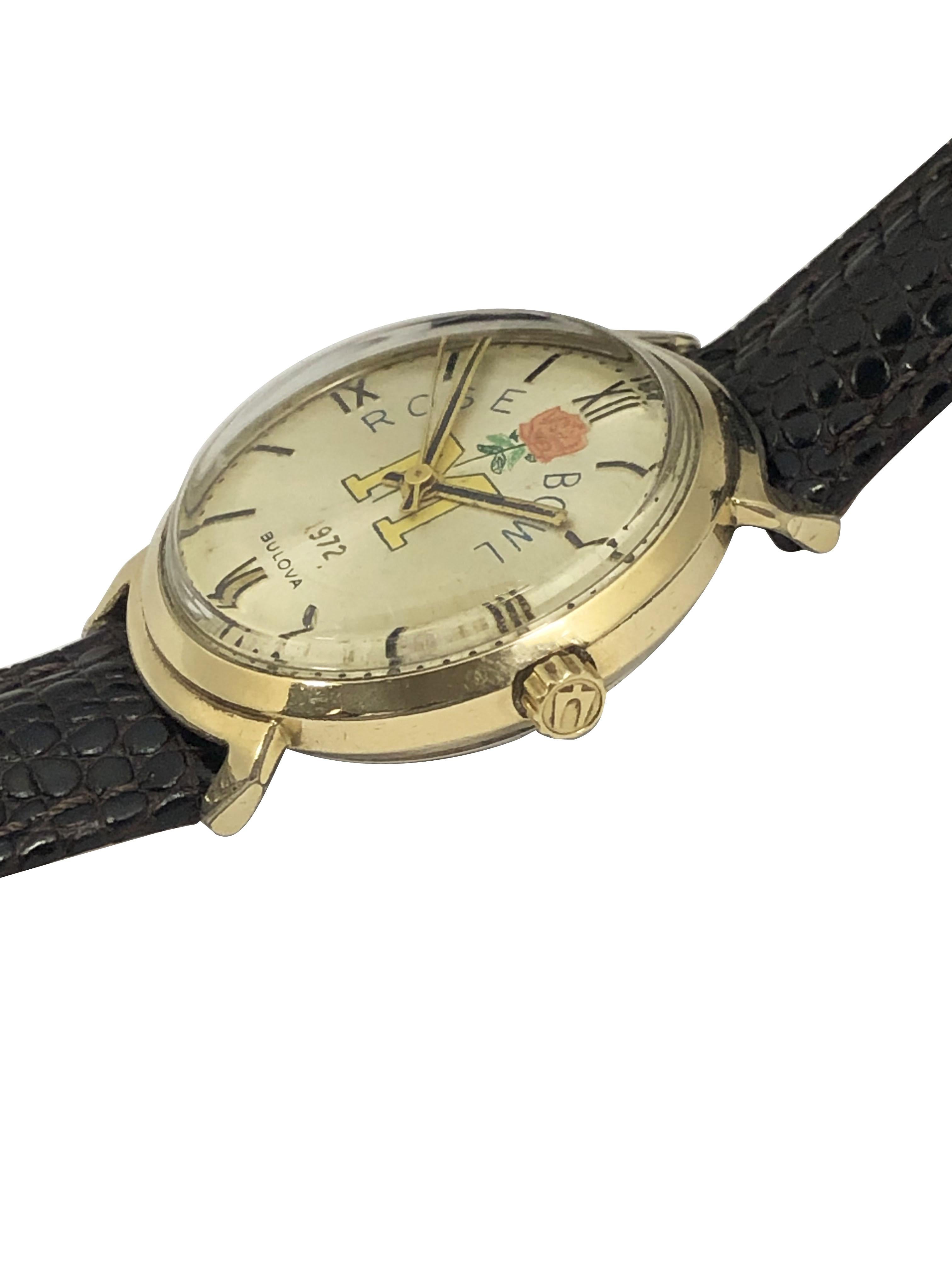 1972 Reloj de pulsera Bulova Rose Bowl, 34 M.M. Placa de oro con fondo de acero inoxidable resistente al agua, esfera satinada de oro claro con impresión personalizada con una M del equipo ganador de Michigan. Movimiento mecánico de cuerda manual de