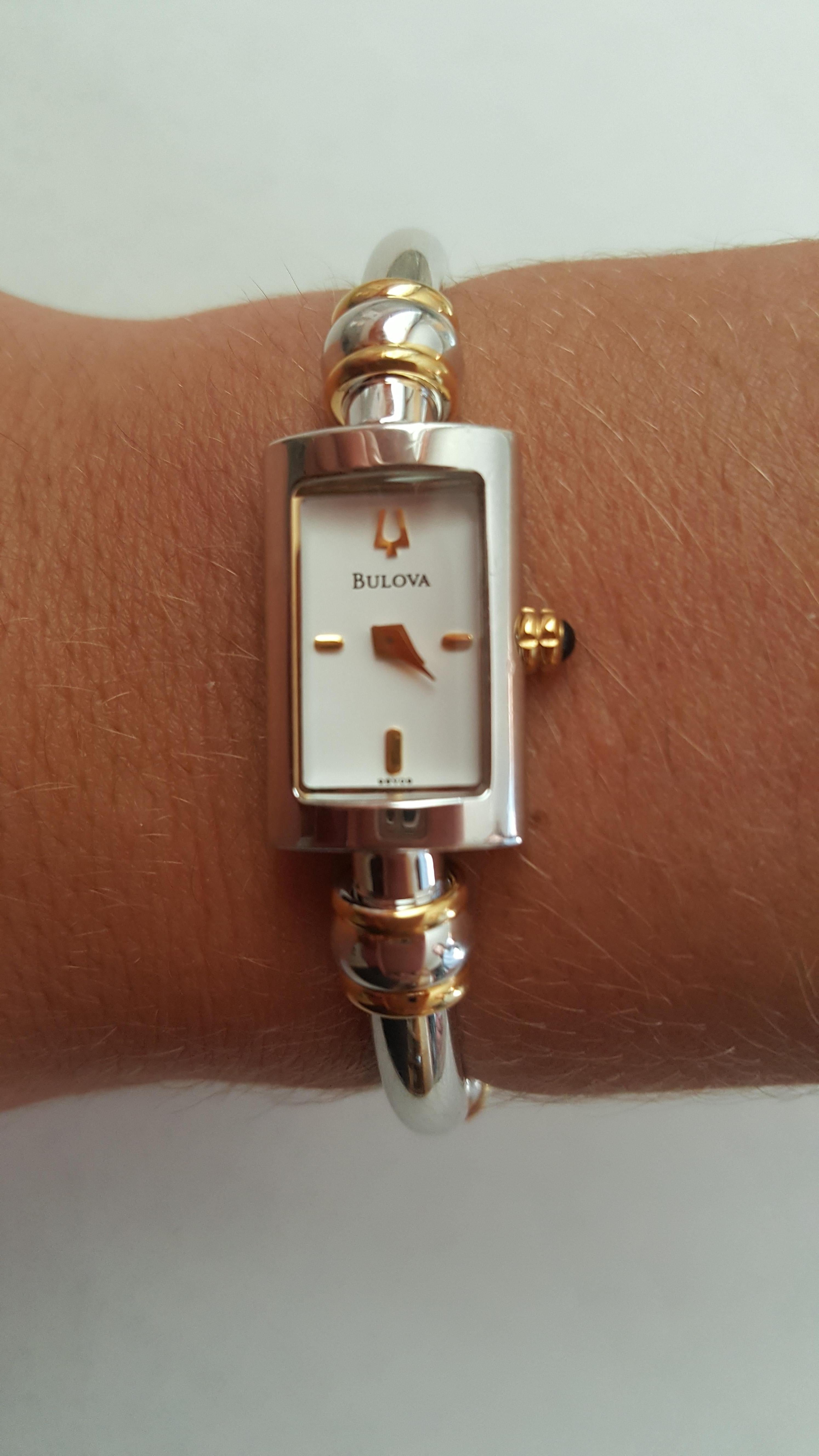 Bulova Ladies Bangle Watch, Model 98V09, Like New. Stainless Steel Case and Bracelet, 14mm by 23 mm, White Face, Water Resistant, Quartz. The watch look as though it may not have been worn, or just a few times.

 White dial with gold-tone hands.